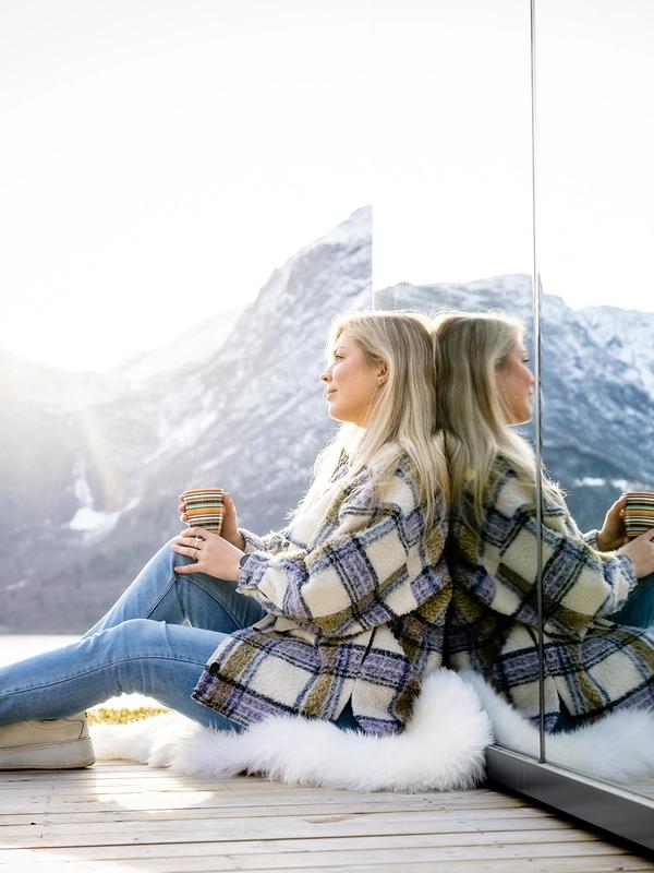 A woman sitting in front of the The Fjord Mirror in Nes Gard in Luster