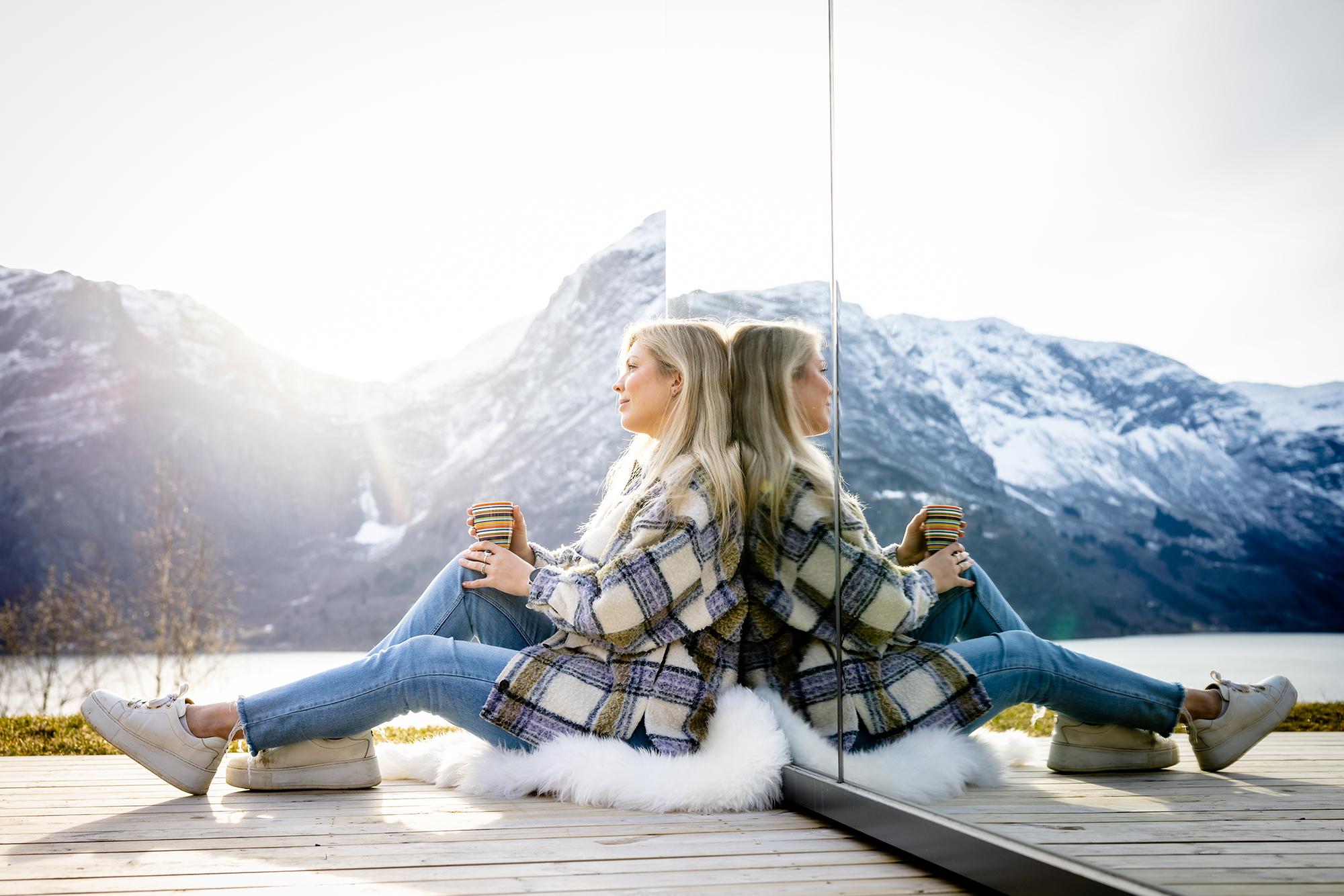 A woman sitting in front of the The Fjord Mirror in Nes Gard in Luster