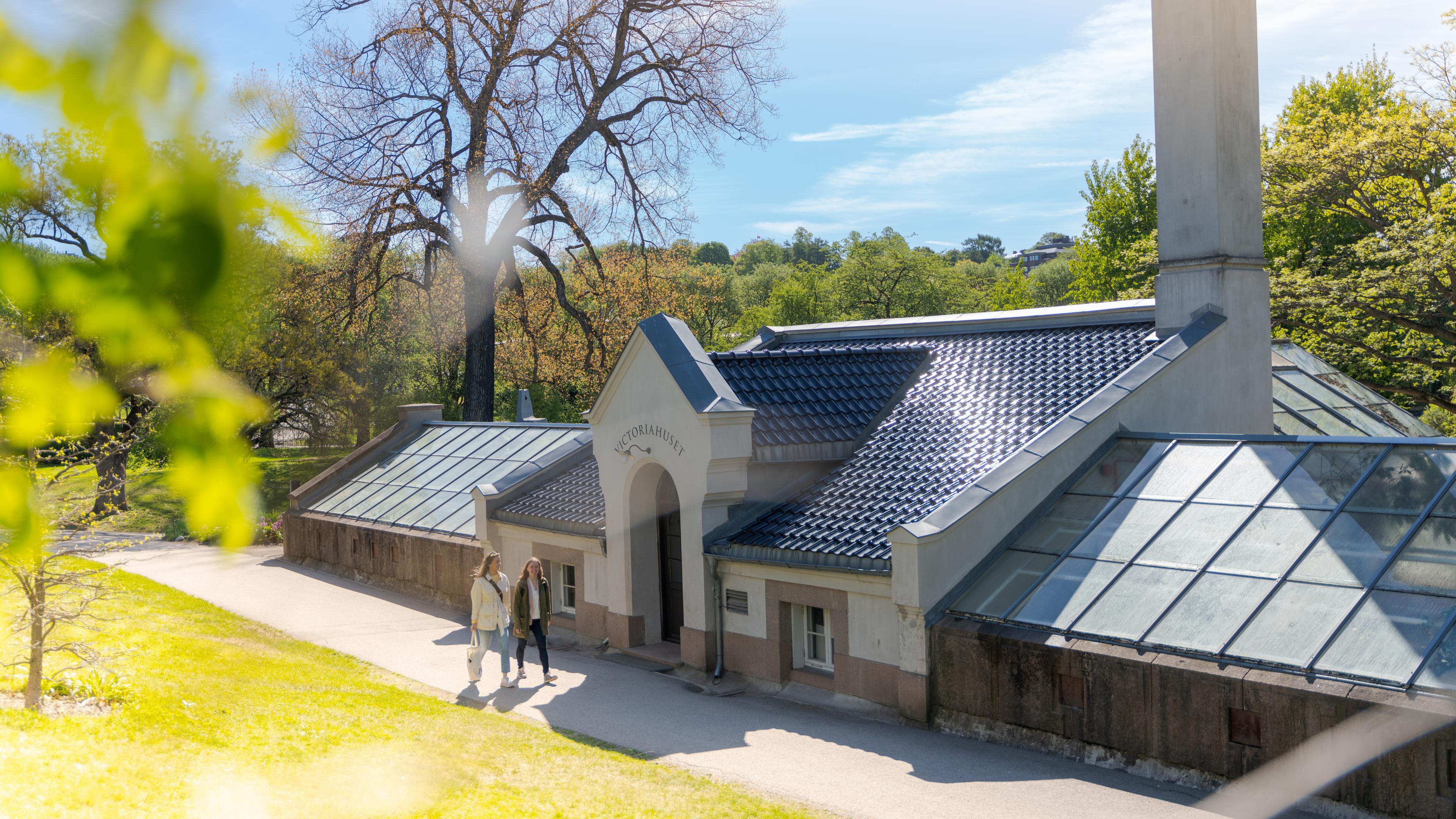 Two friends walking by the Victoria House in the Oslo Botanical Garden