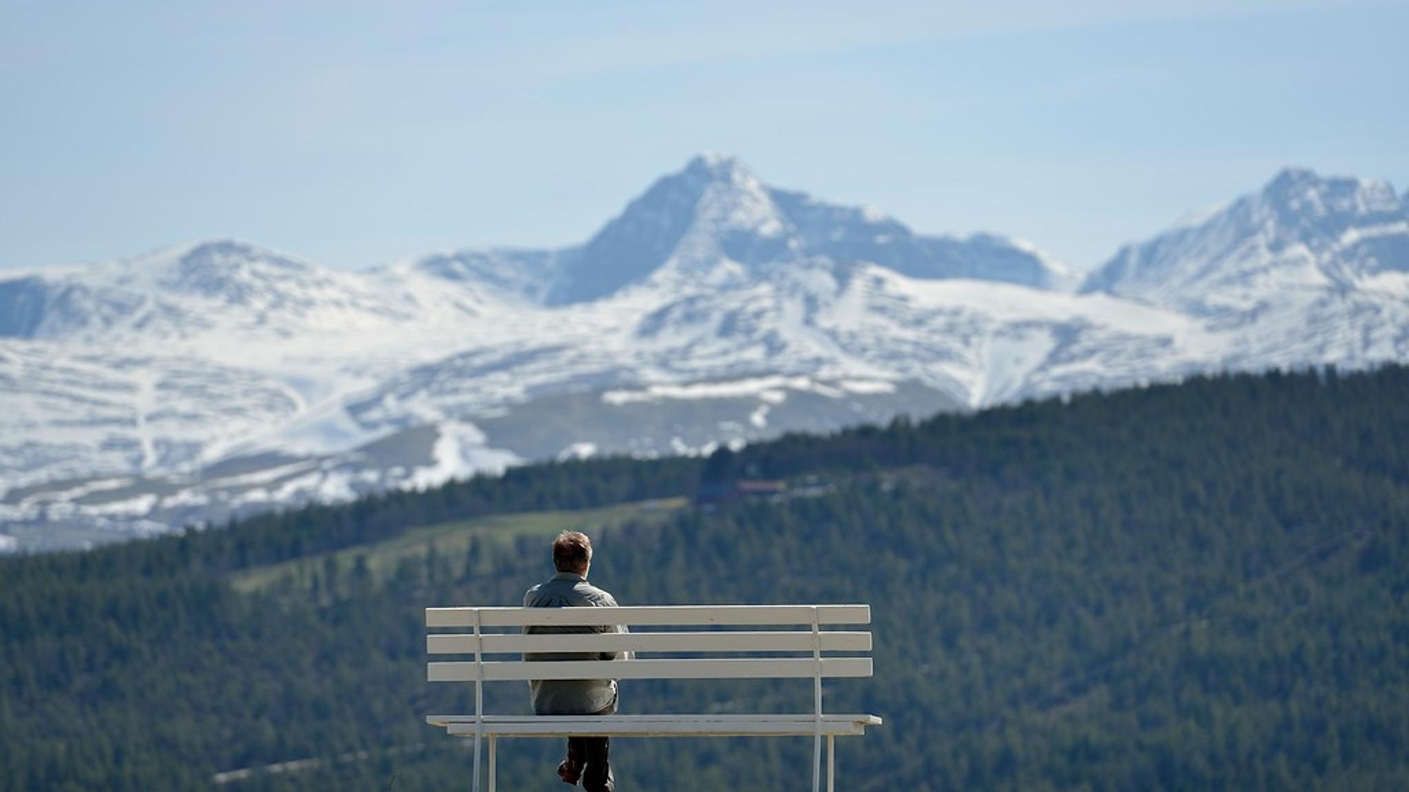 A man on a bench enjoying a mountain view.