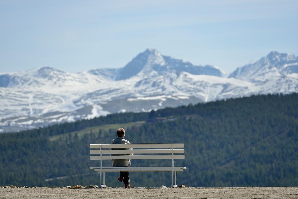 A man on a bench enjoying a mountain view.
