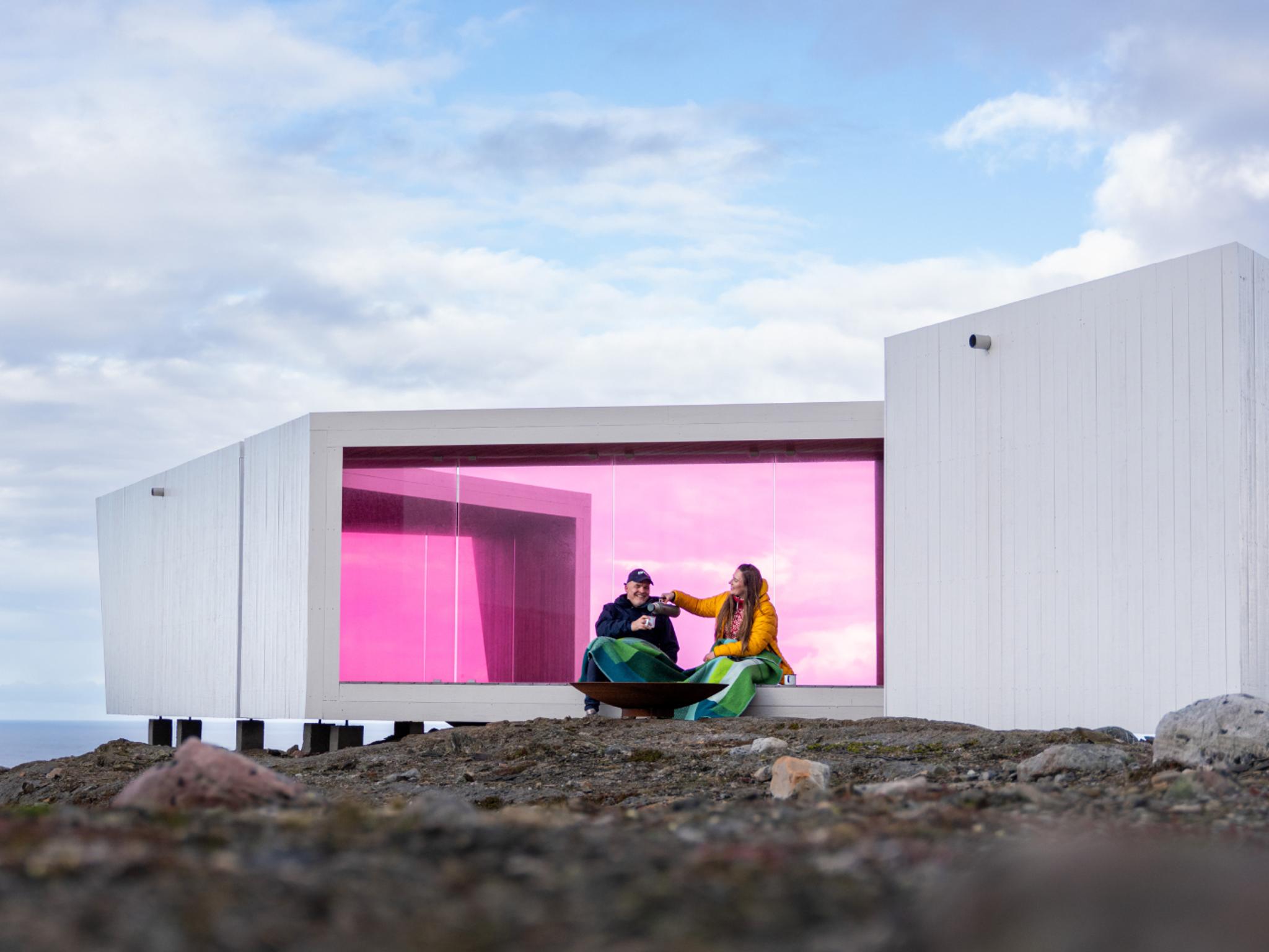 To personer sitter i Domen Viewpoint av Biotope i Varanger, Nord-Norge