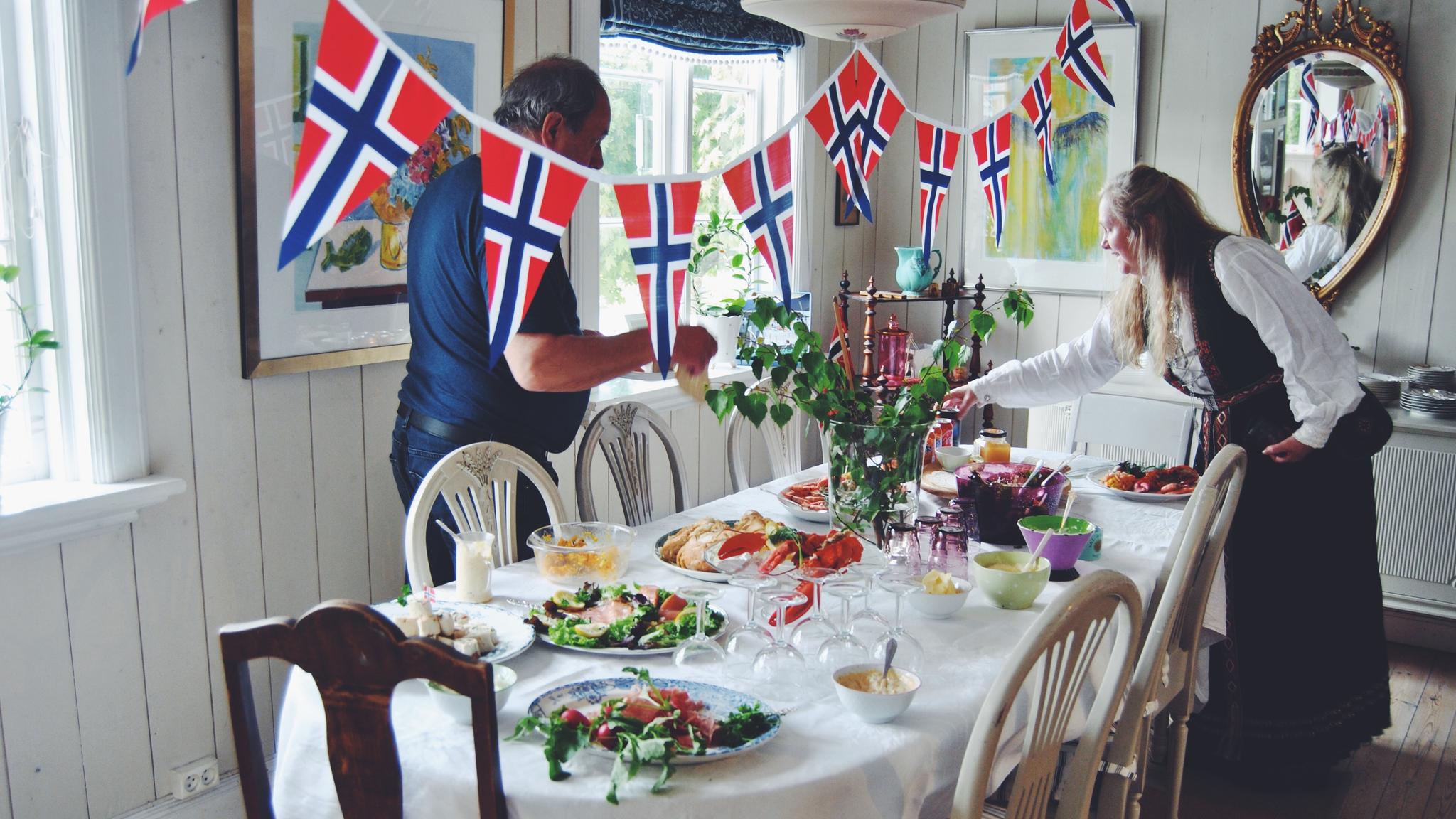 Two people are decorating the table for May 17th, Norway's national day