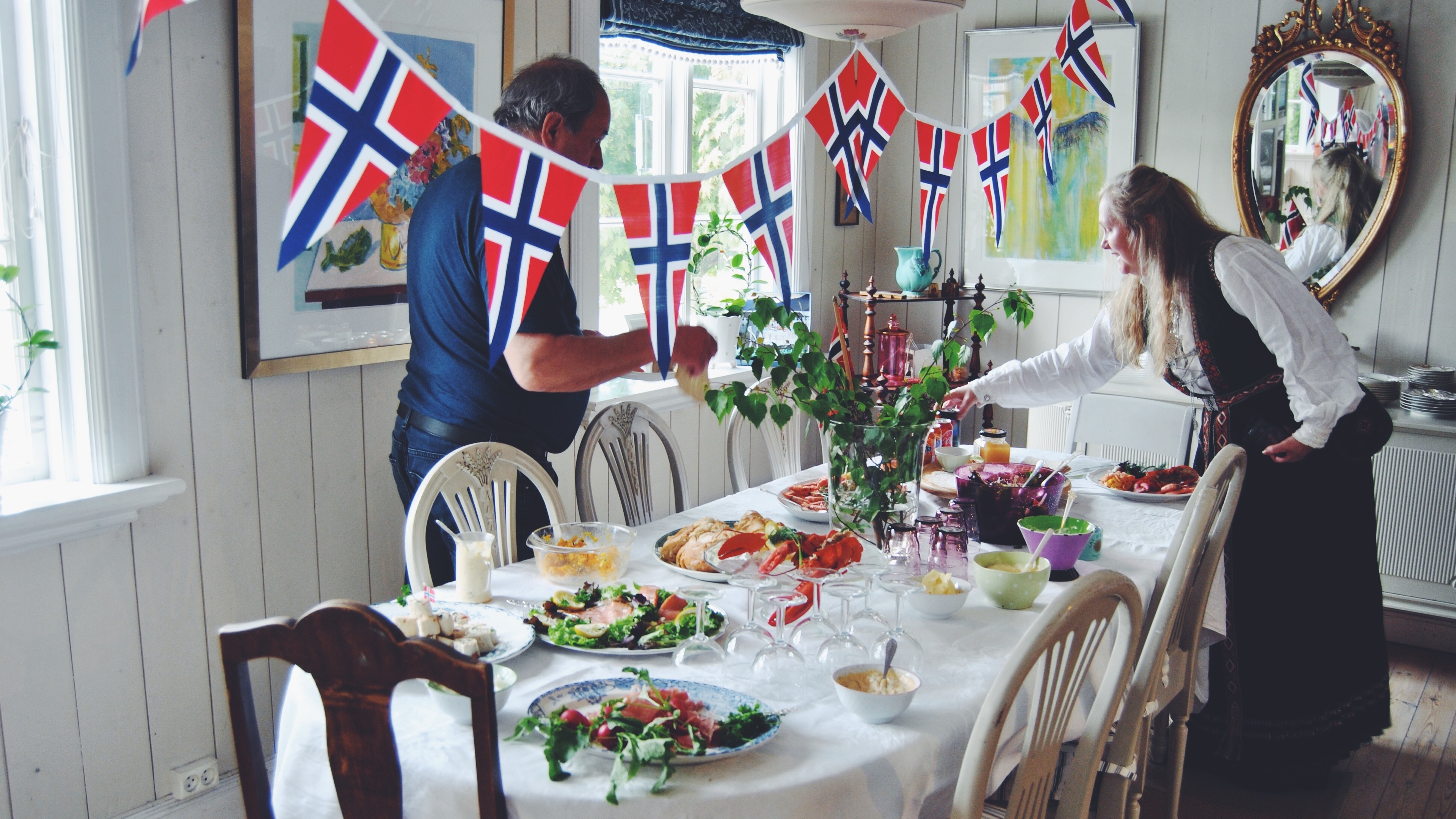 Two people are decorating the table for May 17th, Norway's national day