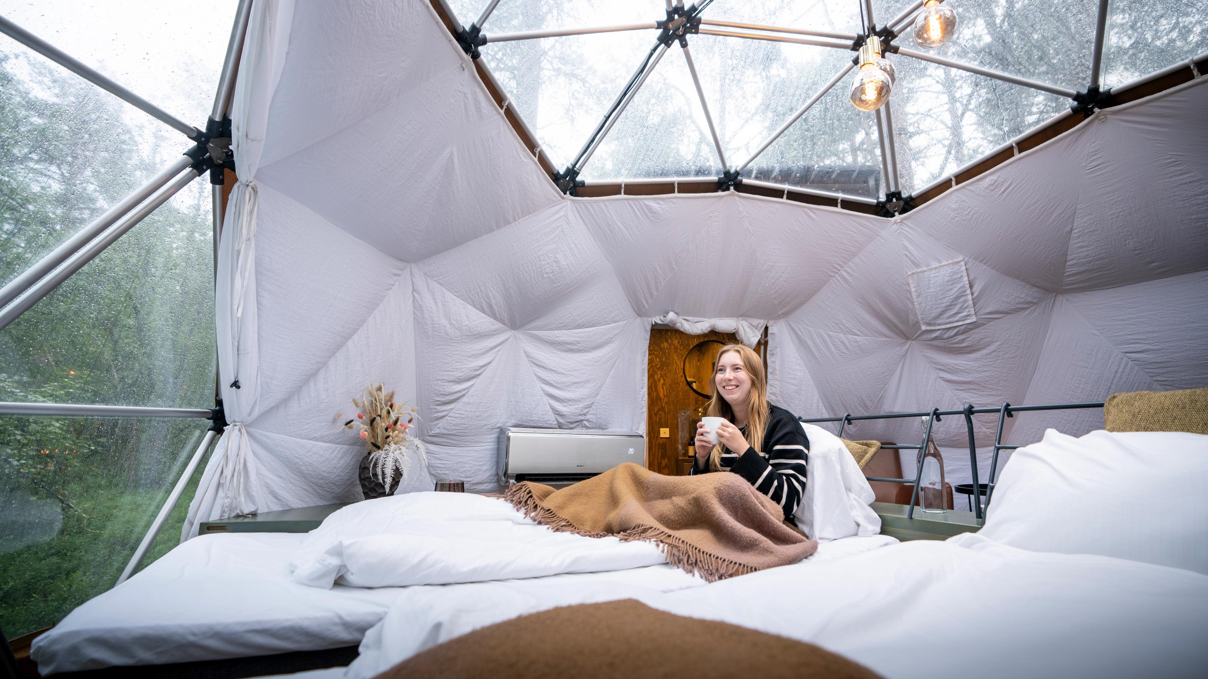 A woman enjoying the view from a Glød Aurora Canvas Dome in Alta