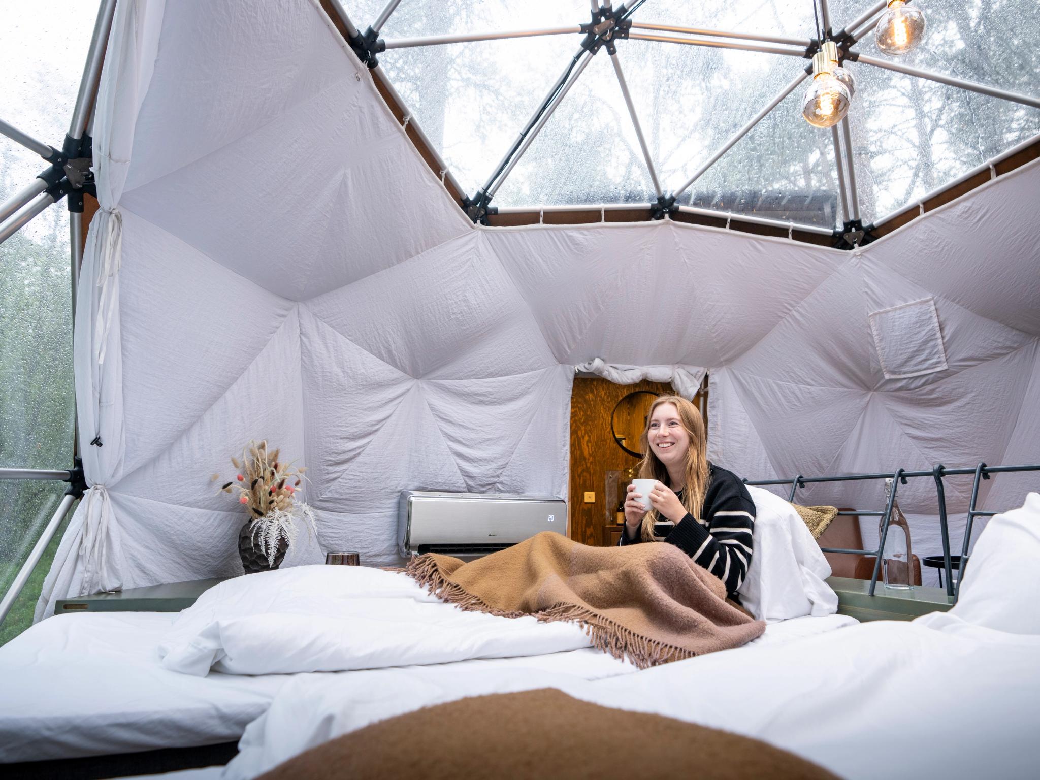 A woman enjoying the view from a Glød Aurora Canvas Dome in Alta