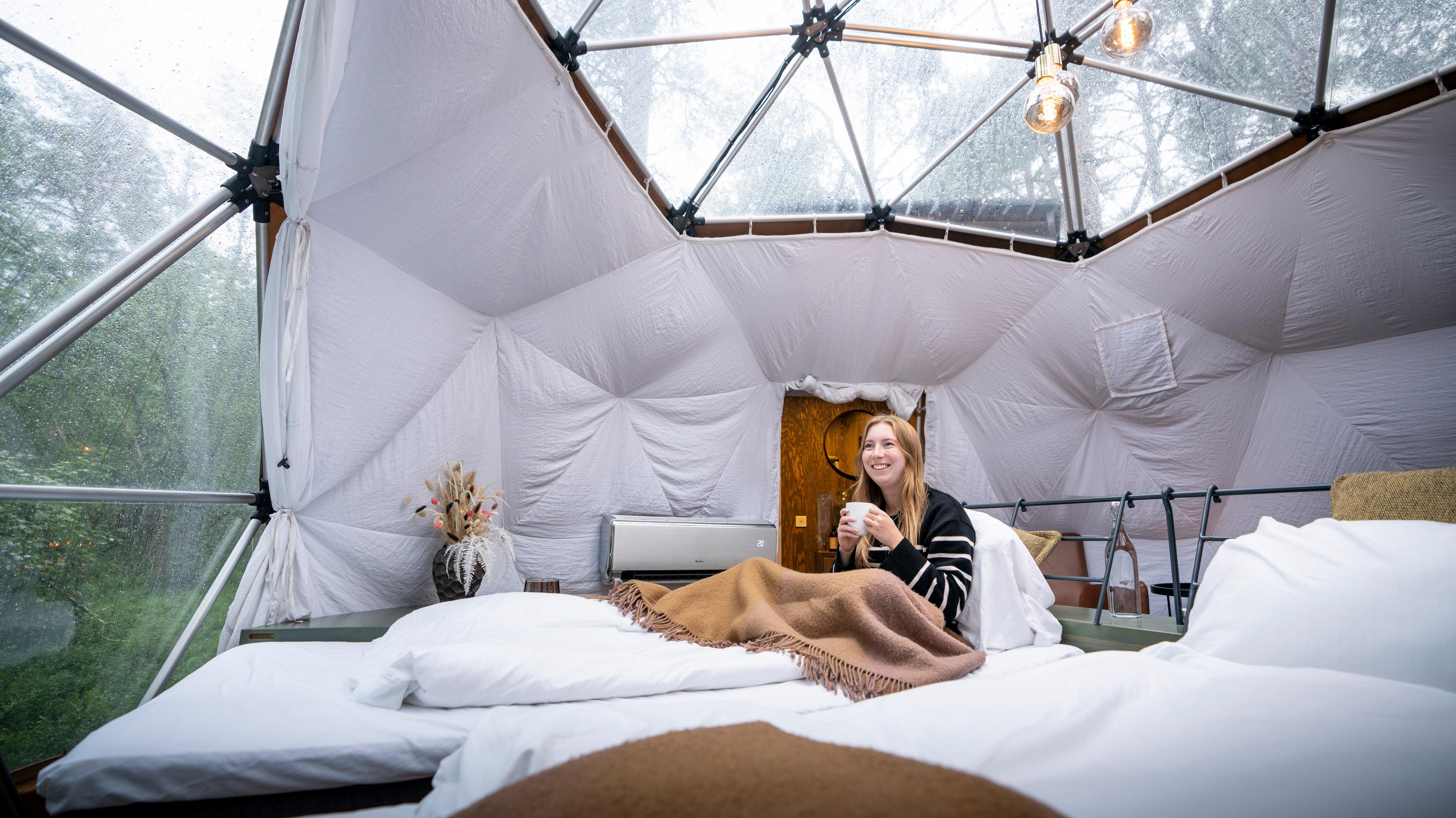 A woman enjoying the view from a Glød Aurora Canvas Dome in Alta