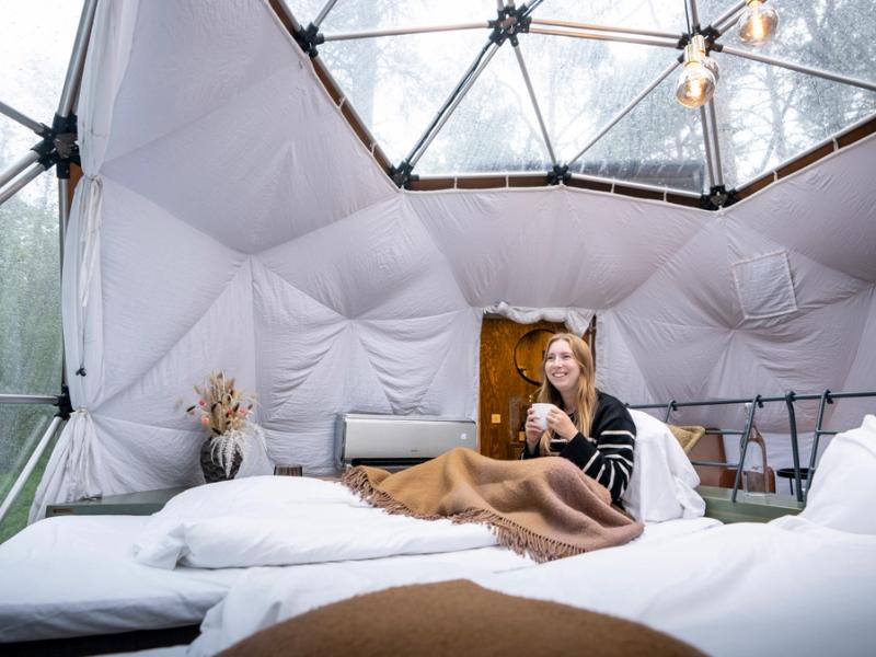 A woman enjoying the view from a Glød Aurora Canvas Dome in Alta