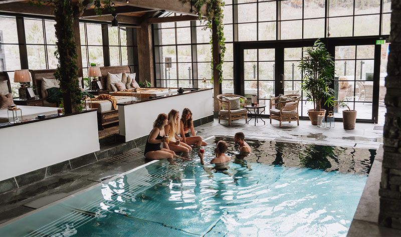 Friends enjoying the pool and spa area at Fyrí Resort, in Hemsedal