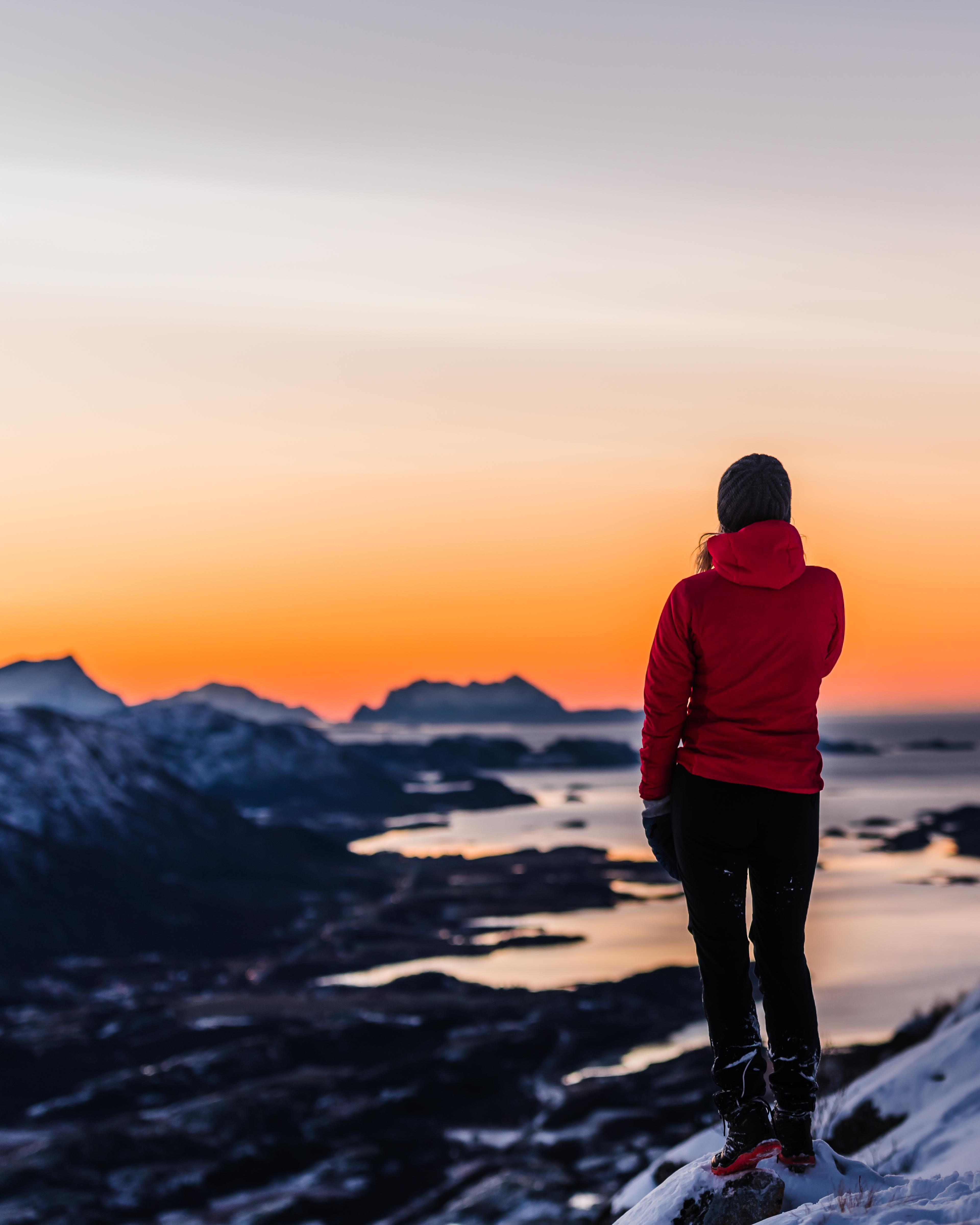 A person looking at the view from a mountain with orange sky.