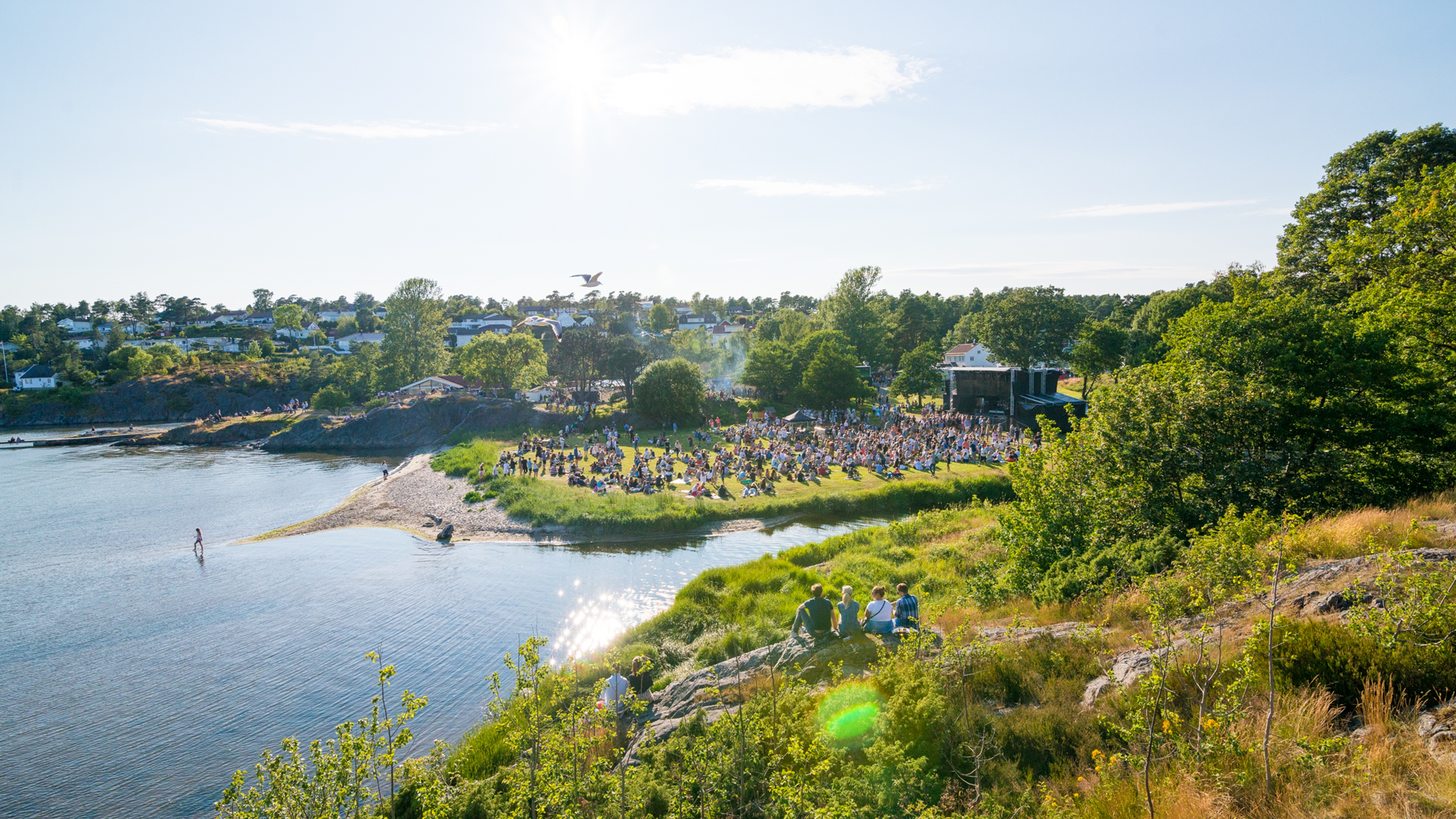 People sitting on the grass by the sea during Skral Festival in Grimstad in Southern Norway
