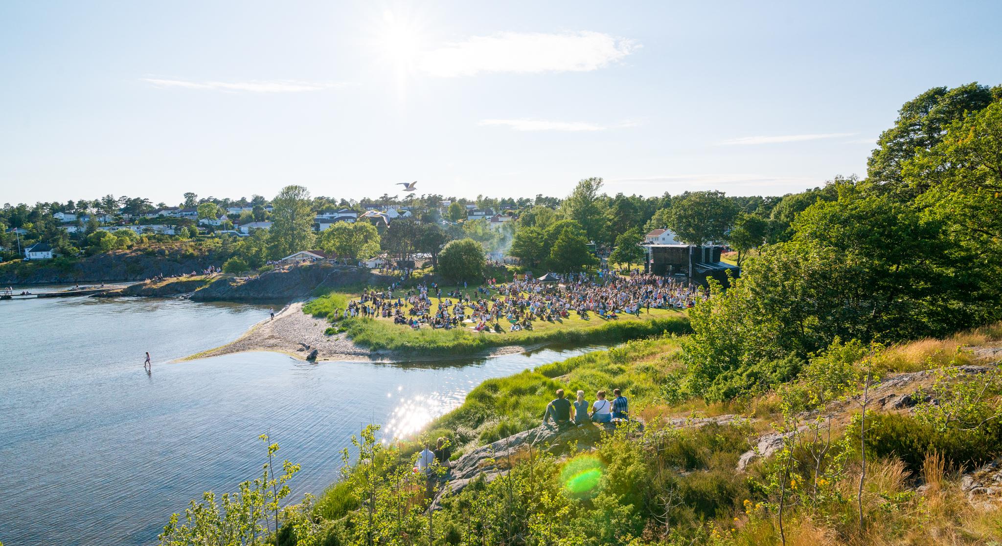 People sitting on the grass by the sea during Skral Festival in Grimstad in Southern Norway