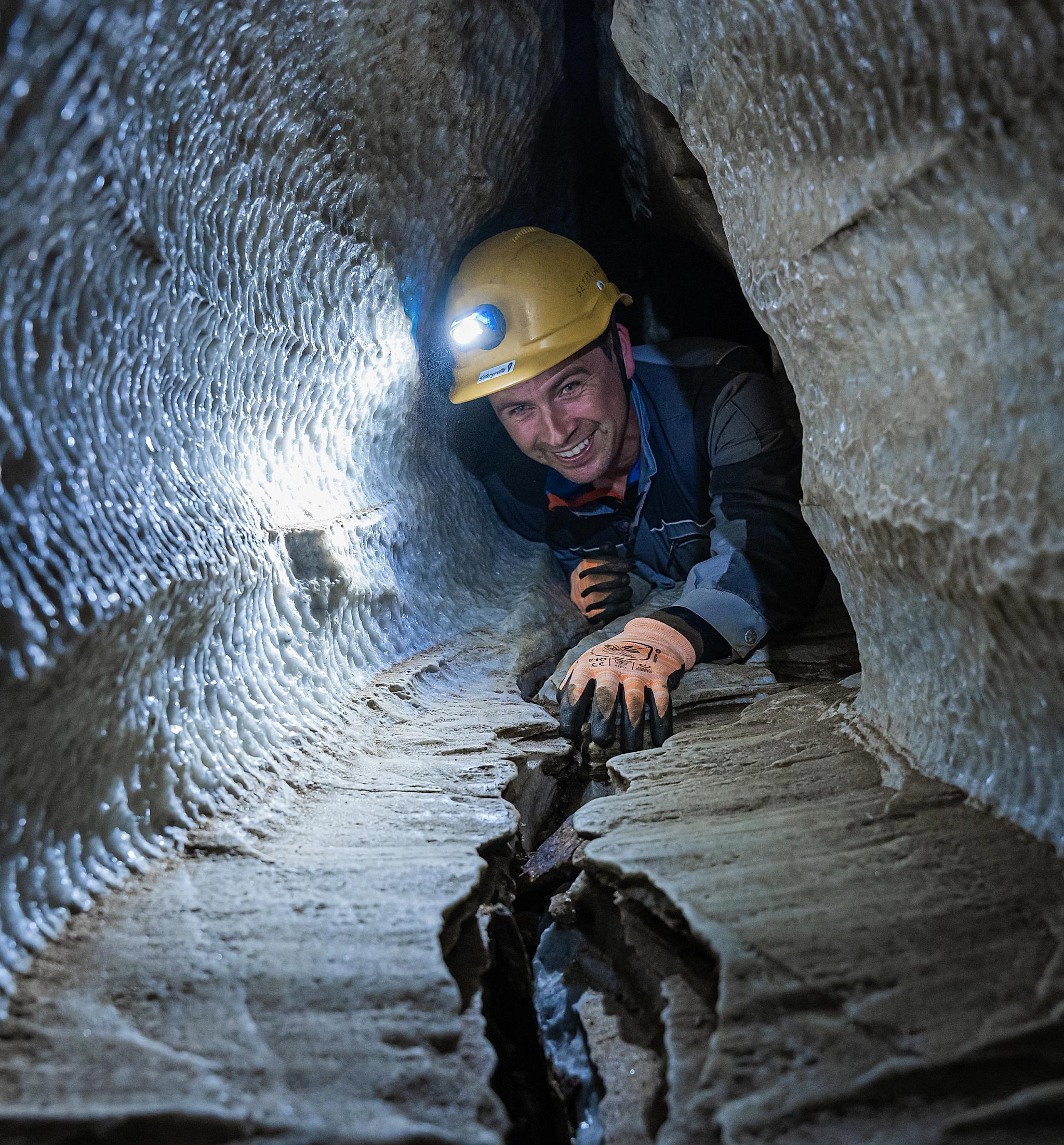 Person with a helmet on a guided tour in Setergrotta in Mo i Rana, Northern Norway