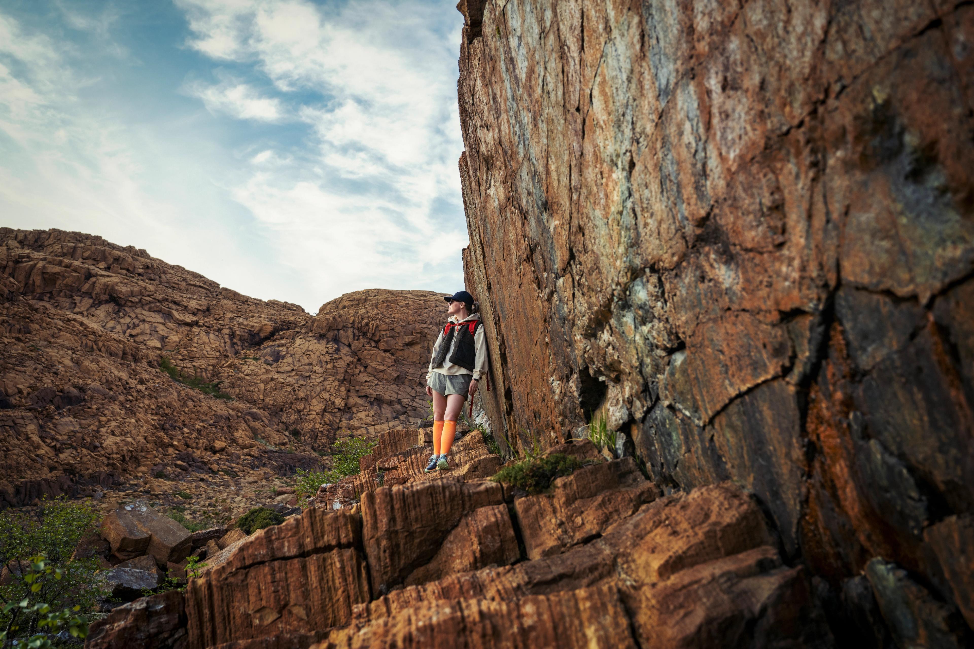 Woman hiking between the red rocks at Leka island in Trøndelag