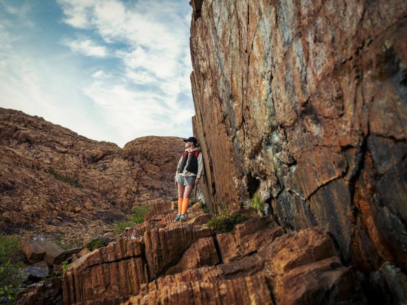 Woman hiking between the red rocks at Leka island in Trøndelag