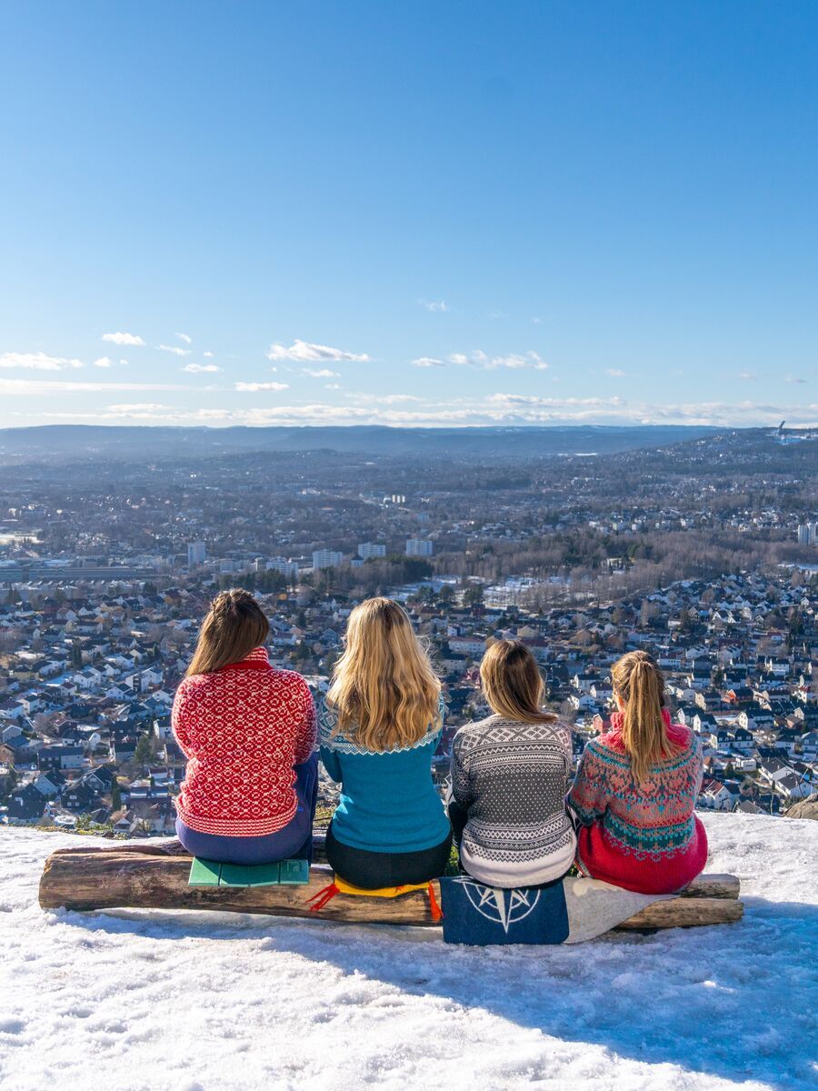 Women sit and watch the view of Oslo in knitted overalls, Norway.