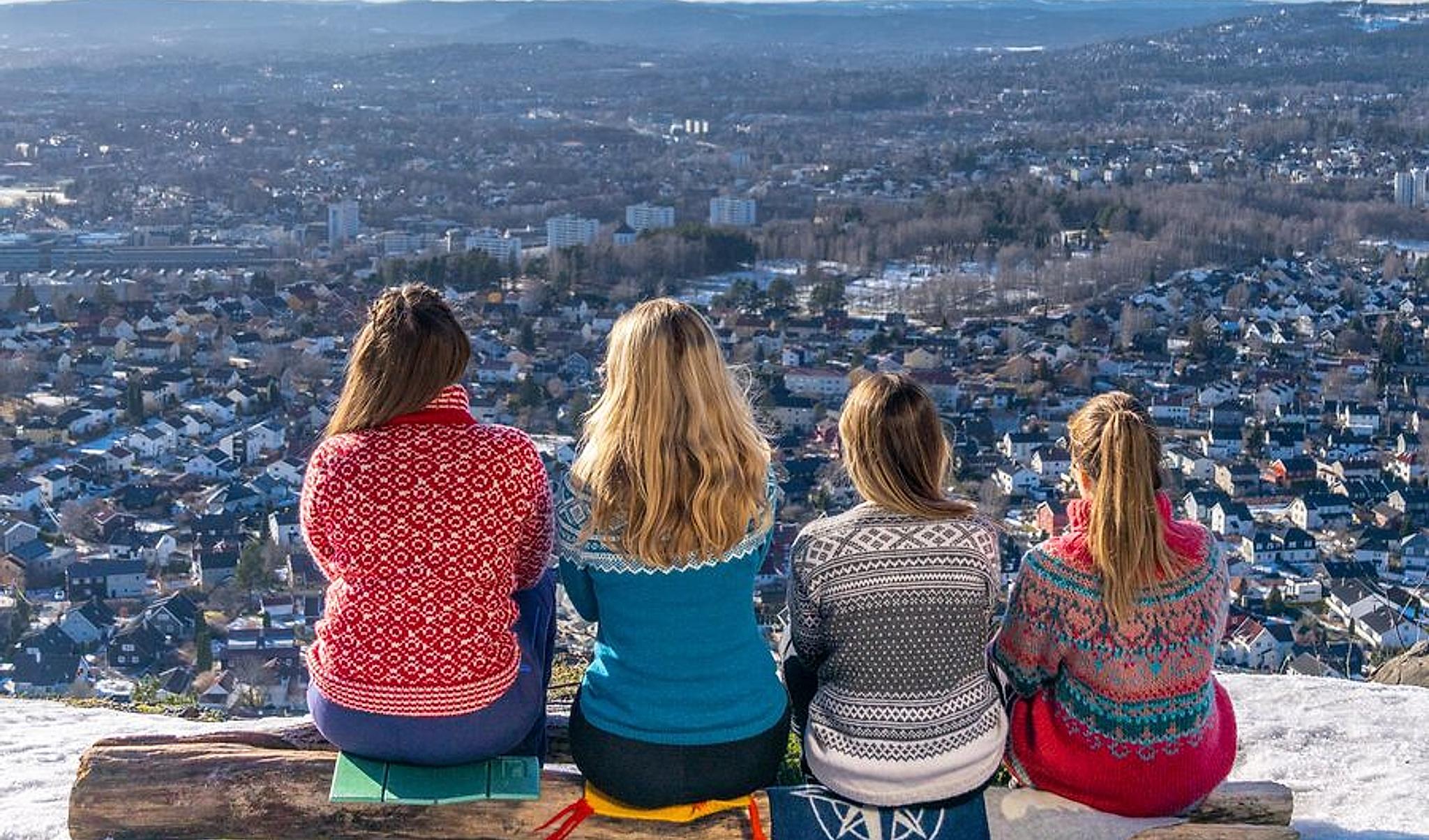 Women sit and watch the view of Oslo in knitted overalls, Norway.