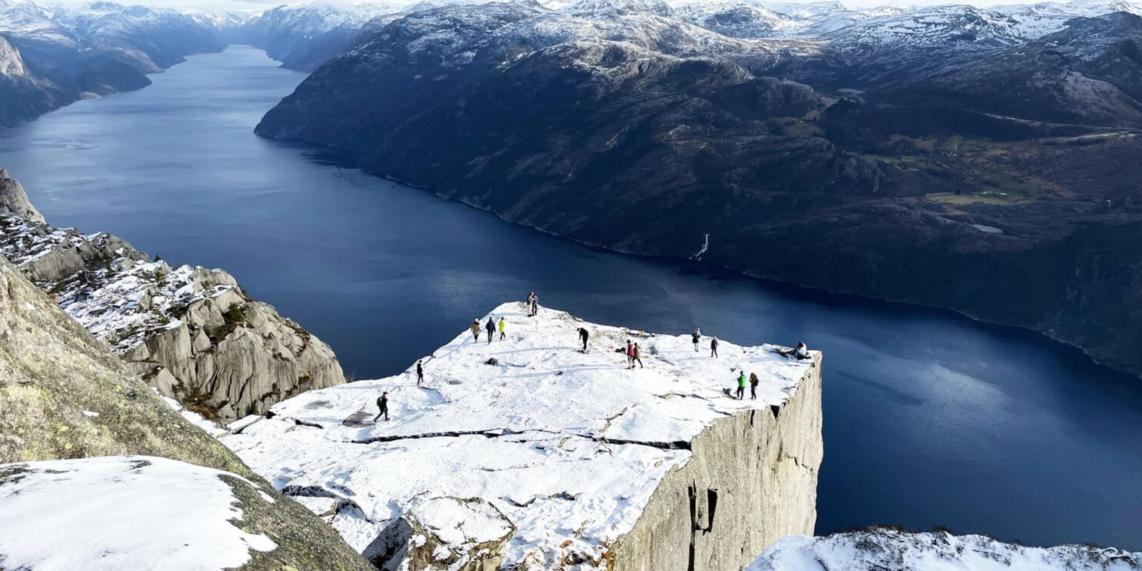 Two men standing on Preikestolen, the Pulpit Rock, looking out over Lysefjord