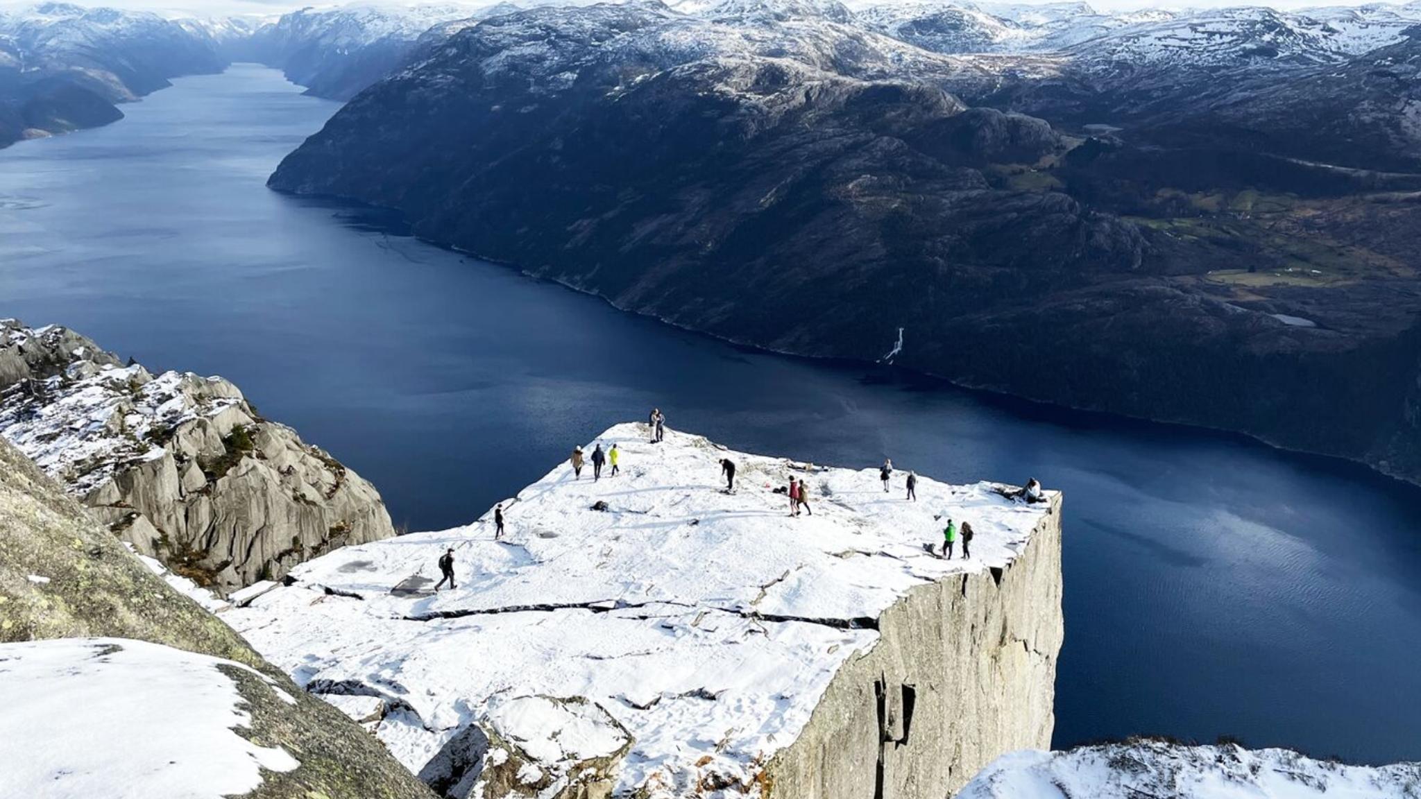 Two men standing on Preikestolen, the Pulpit Rock, looking out over Lysefjord