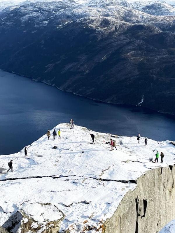 Two men standing on Preikestolen, the Pulpit Rock, looking out over Lysefjord