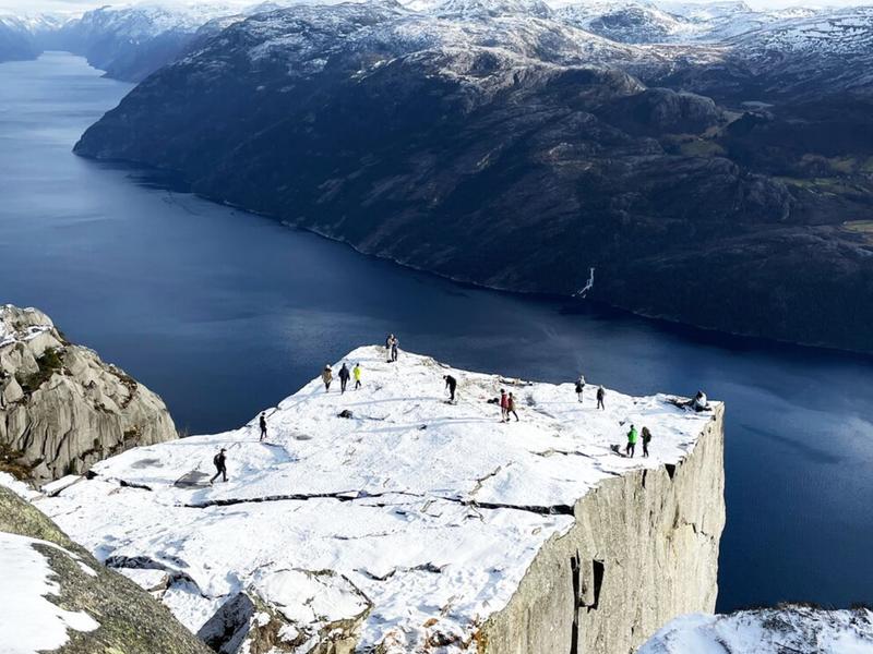 Two men standing on Preikestolen, the Pulpit Rock, looking out over Lysefjord