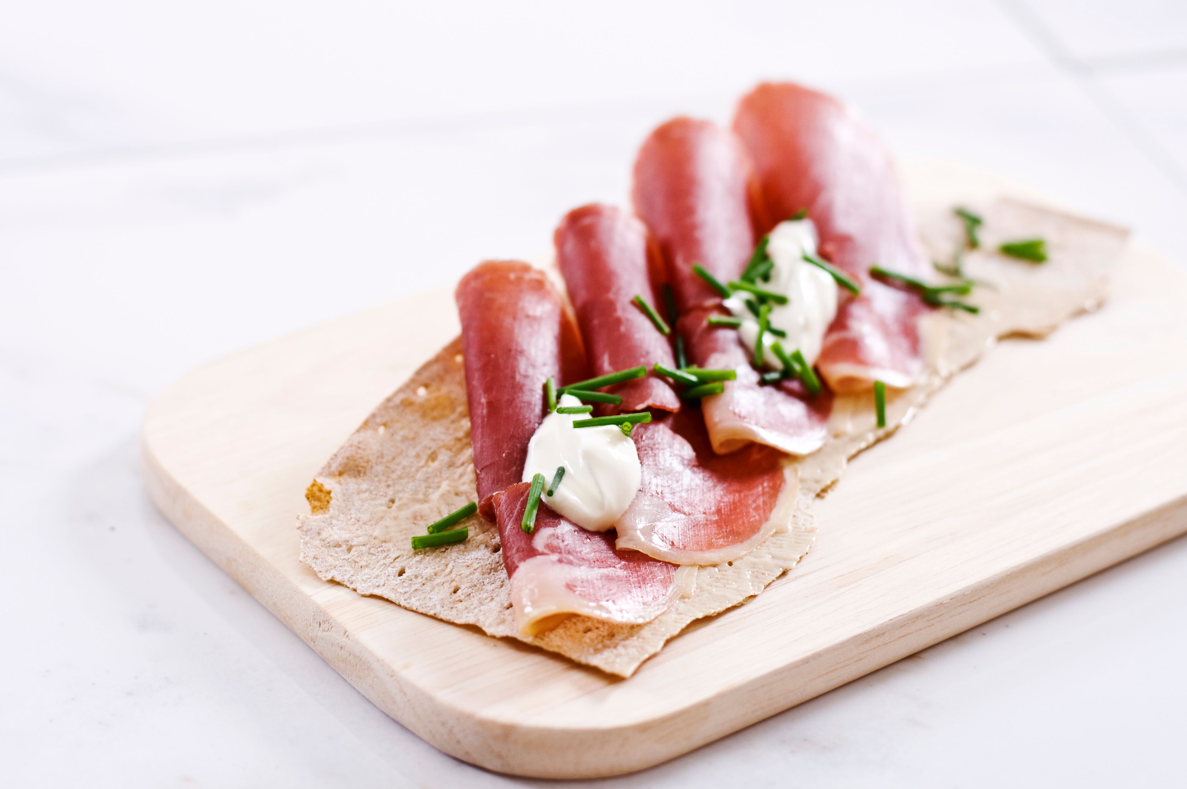 Norwegian flatbrød (flat-bread) served with sliced fenalår served on a wooden platter in Norway