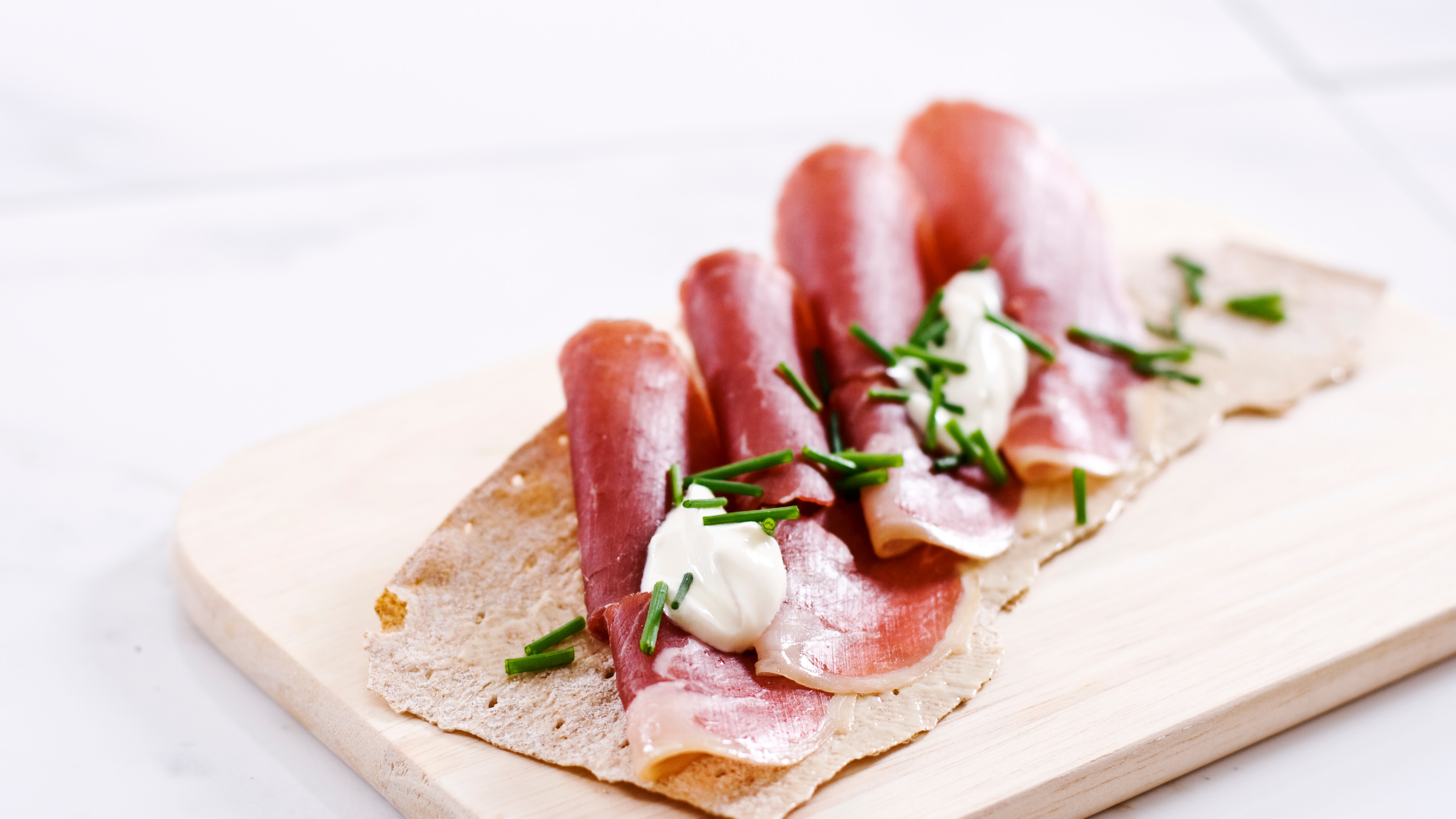 Norwegian flatbrød (flat-bread) served with sliced fenalår served on a wooden platter in Norway