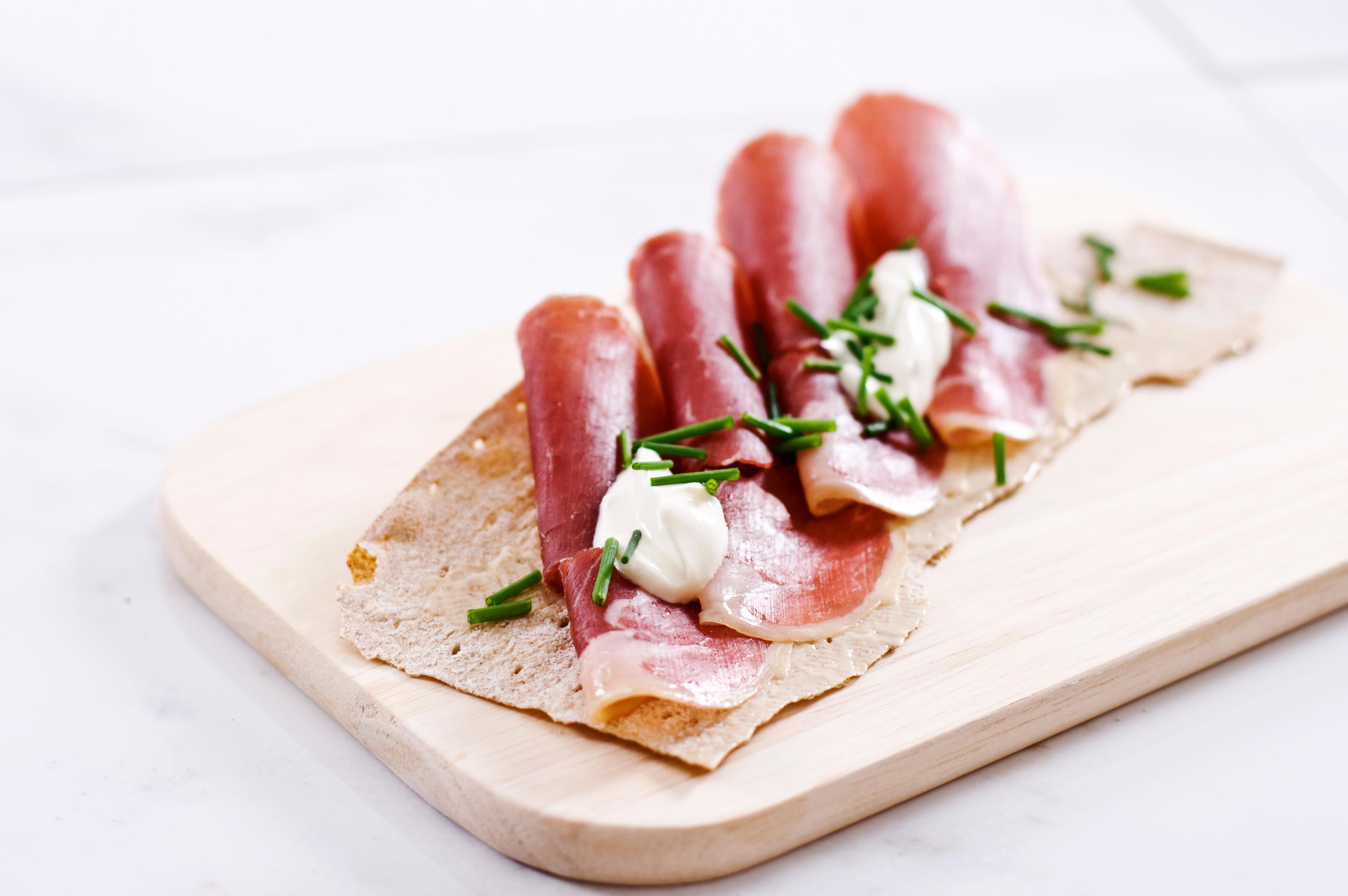Norwegian flatbrød (flat-bread) served with sliced fenalår served on a wooden platter in Norway