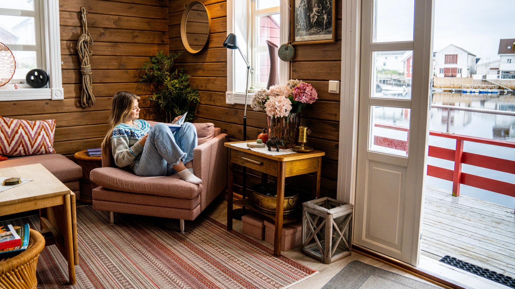 A woman reading a book in a fisherman's cabin by the sea, at Veiholmen outside Smøla in the Northwest