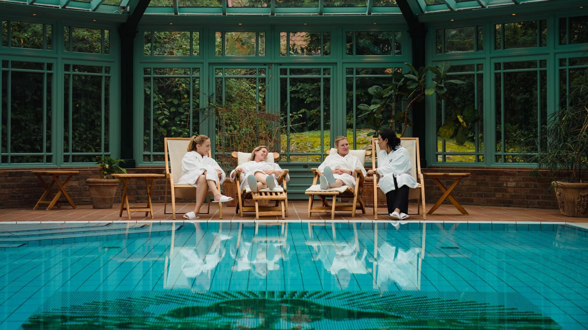 Fyra kvinnor kopplar av vid poolen på Engø Gård vid Tjøme i regionen Østlandet (östra Norge)