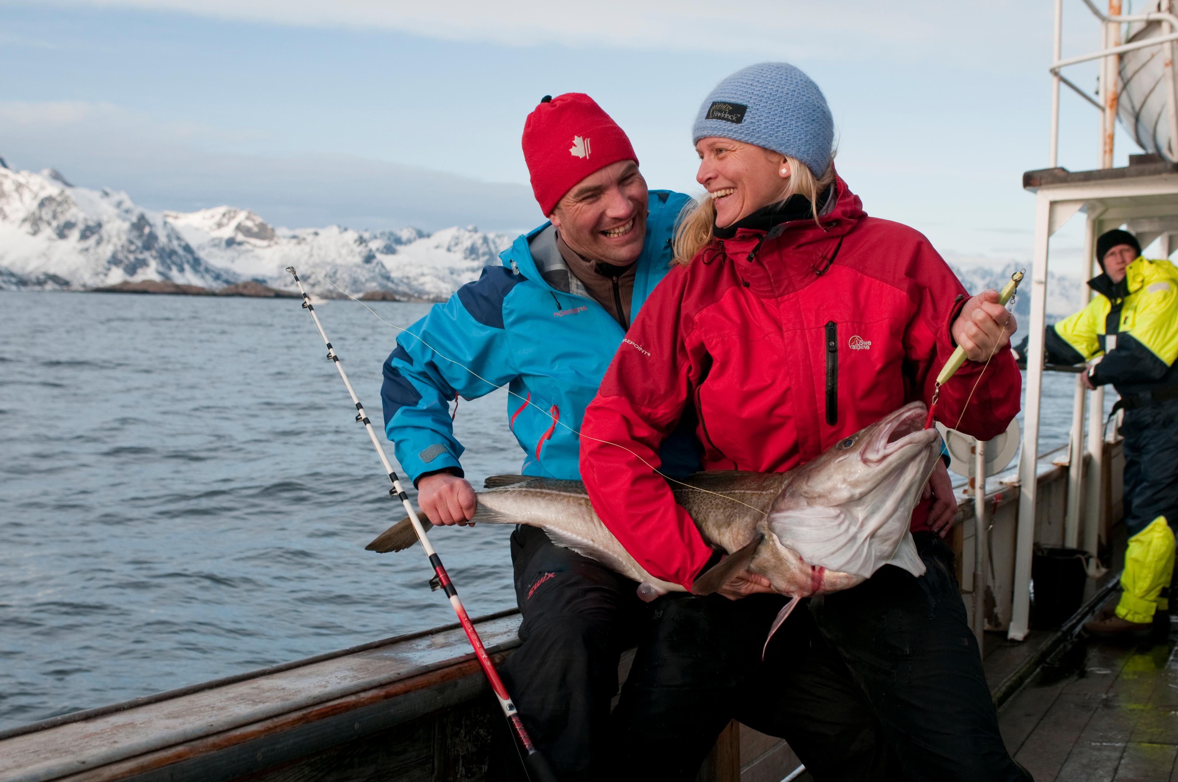 Un hombre y una mujer sujetan un gran ejemplar de bacalao recién pescado en Lofoten, en el Norte de Noruega.