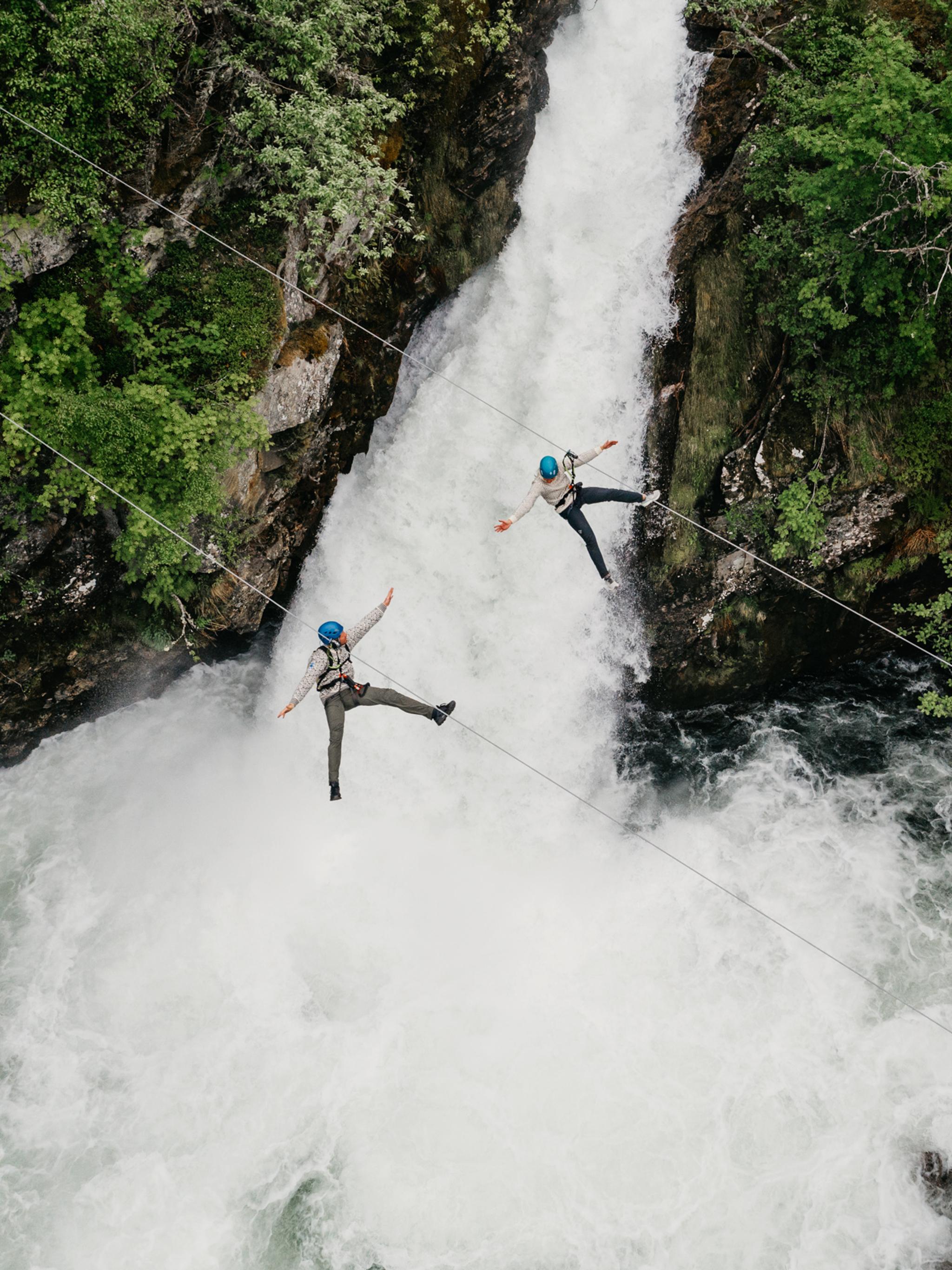 Couple ziplining over waterfall in Geiranger