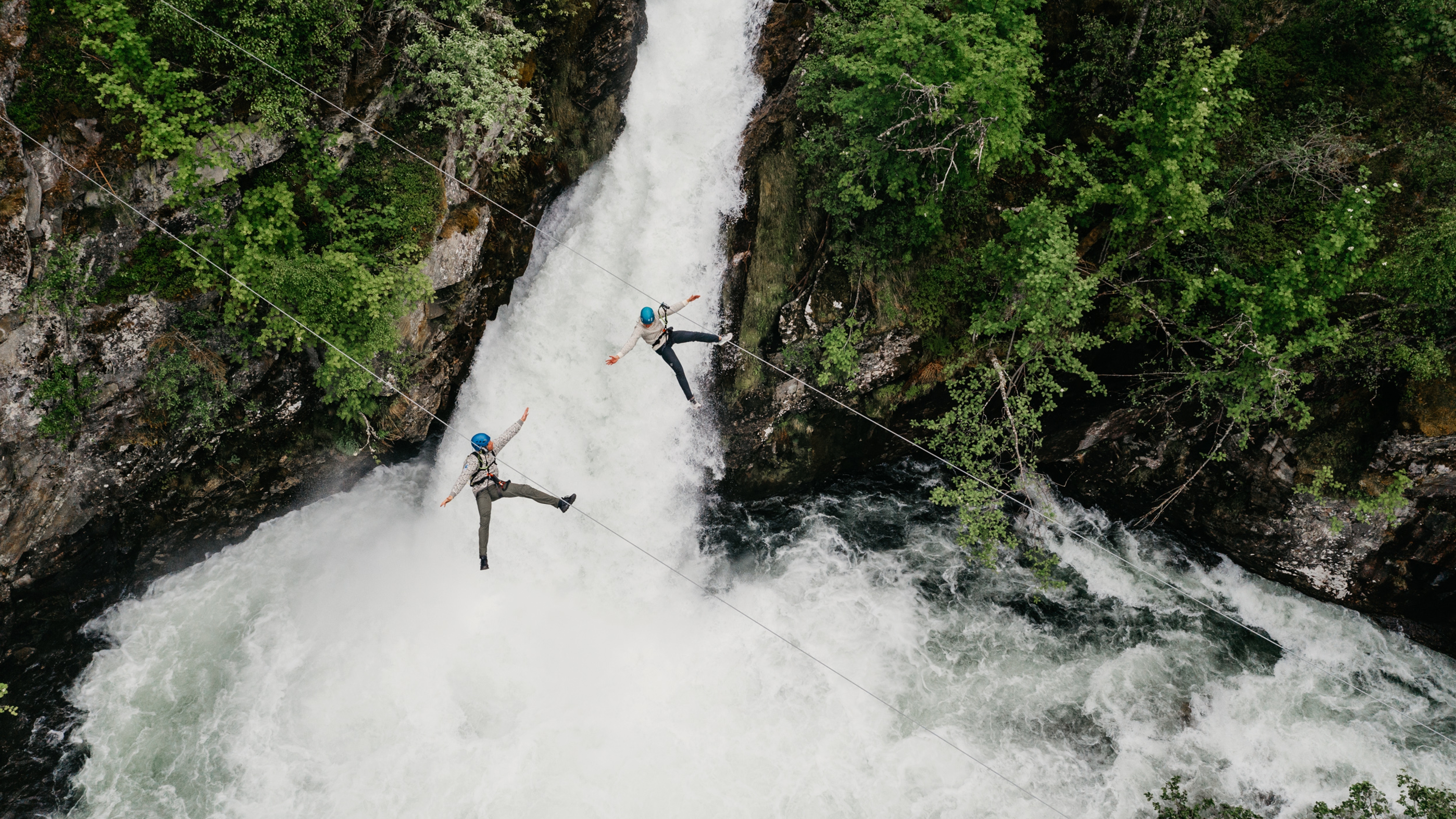 Couple ziplining over waterfall in Geiranger