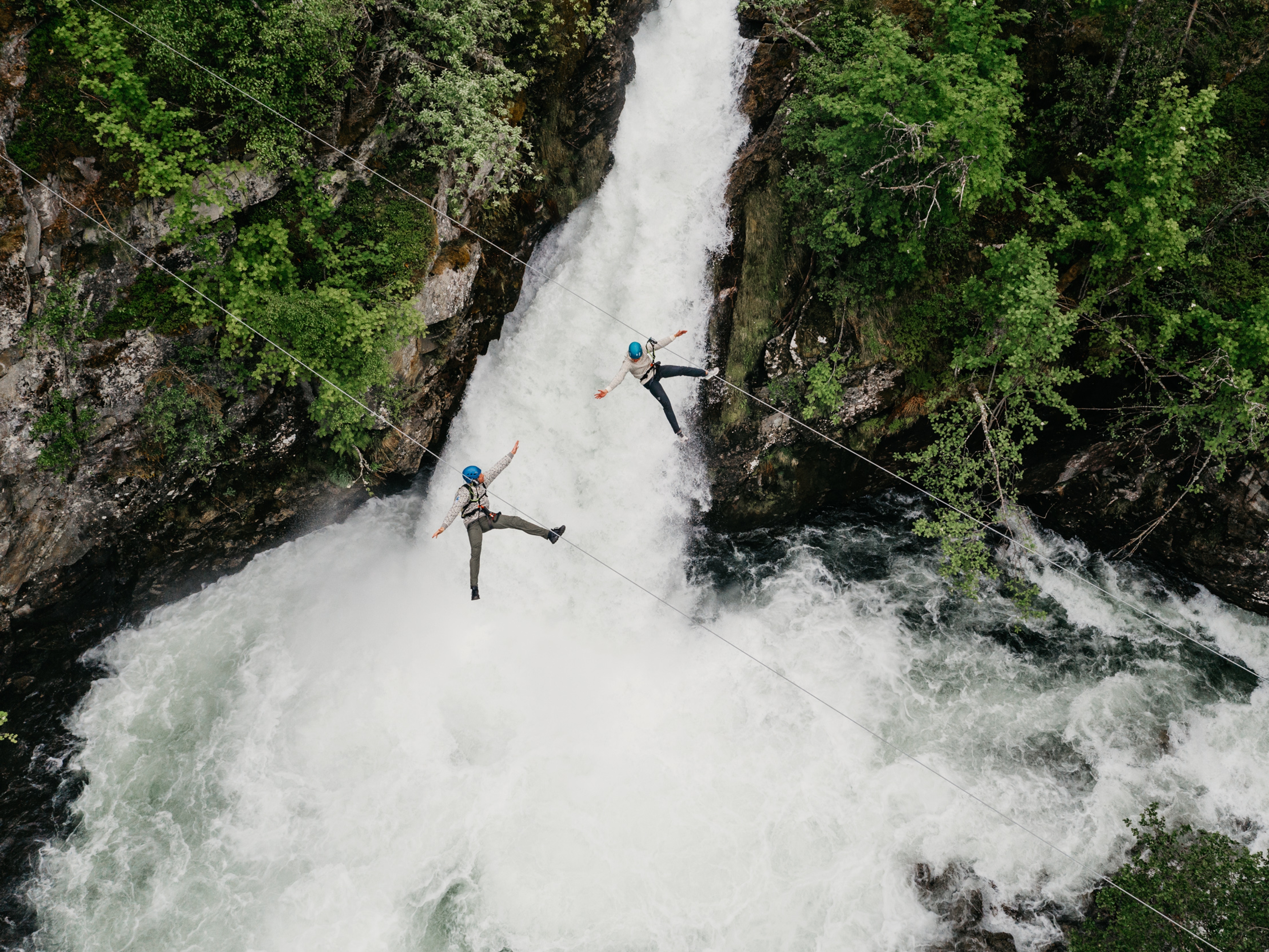Couple ziplining over waterfall in Geiranger