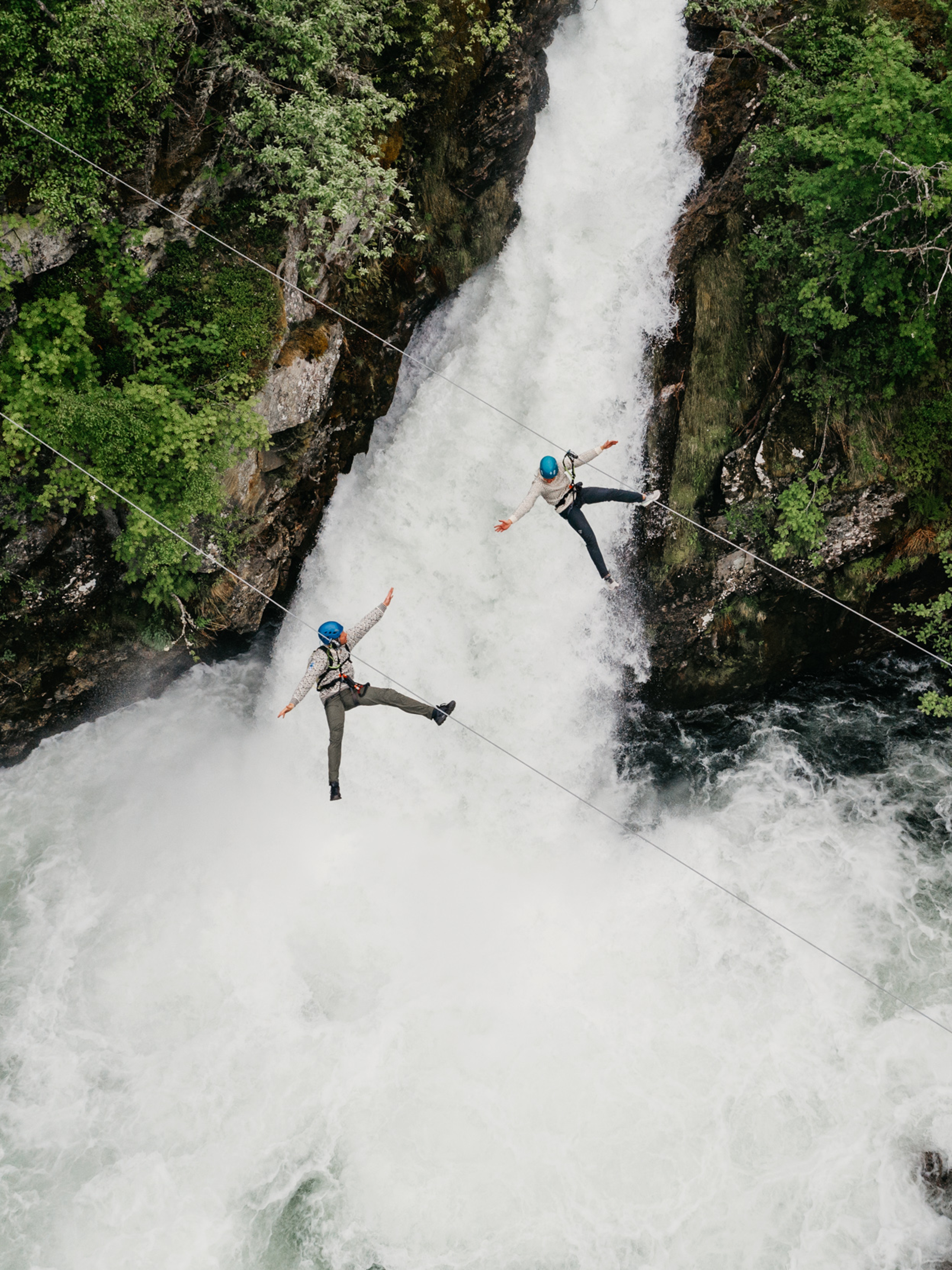 Couple ziplining over waterfall in Geiranger
