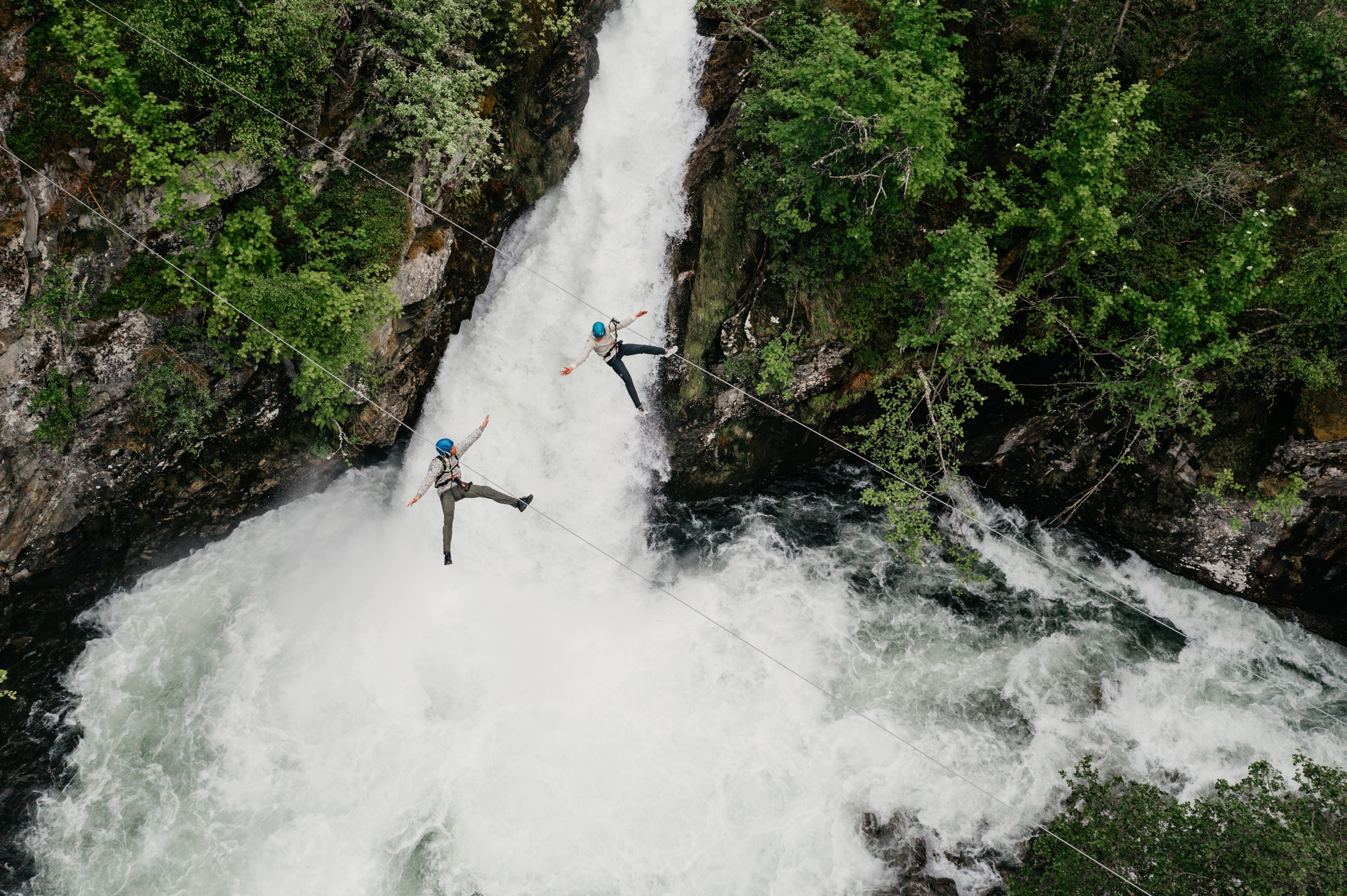 Couple ziplining over waterfall in Geiranger