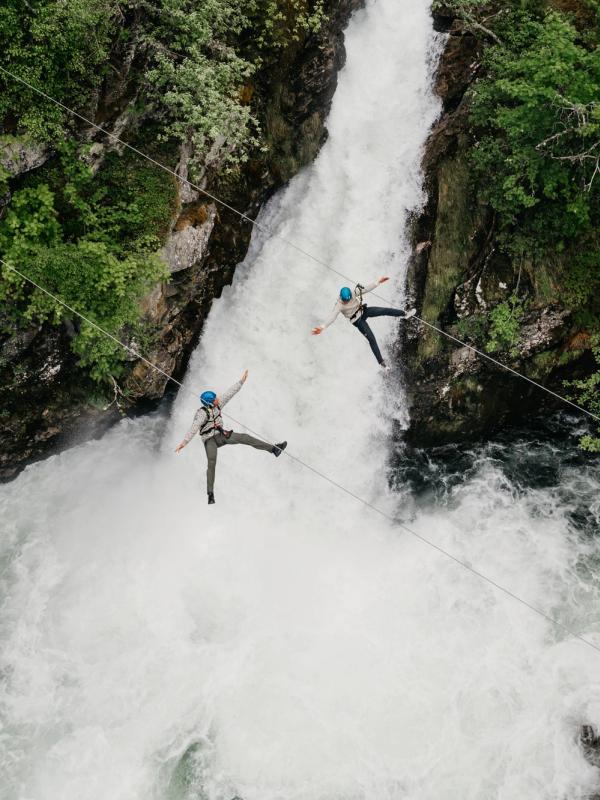 Couple ziplining over waterfall in Geiranger