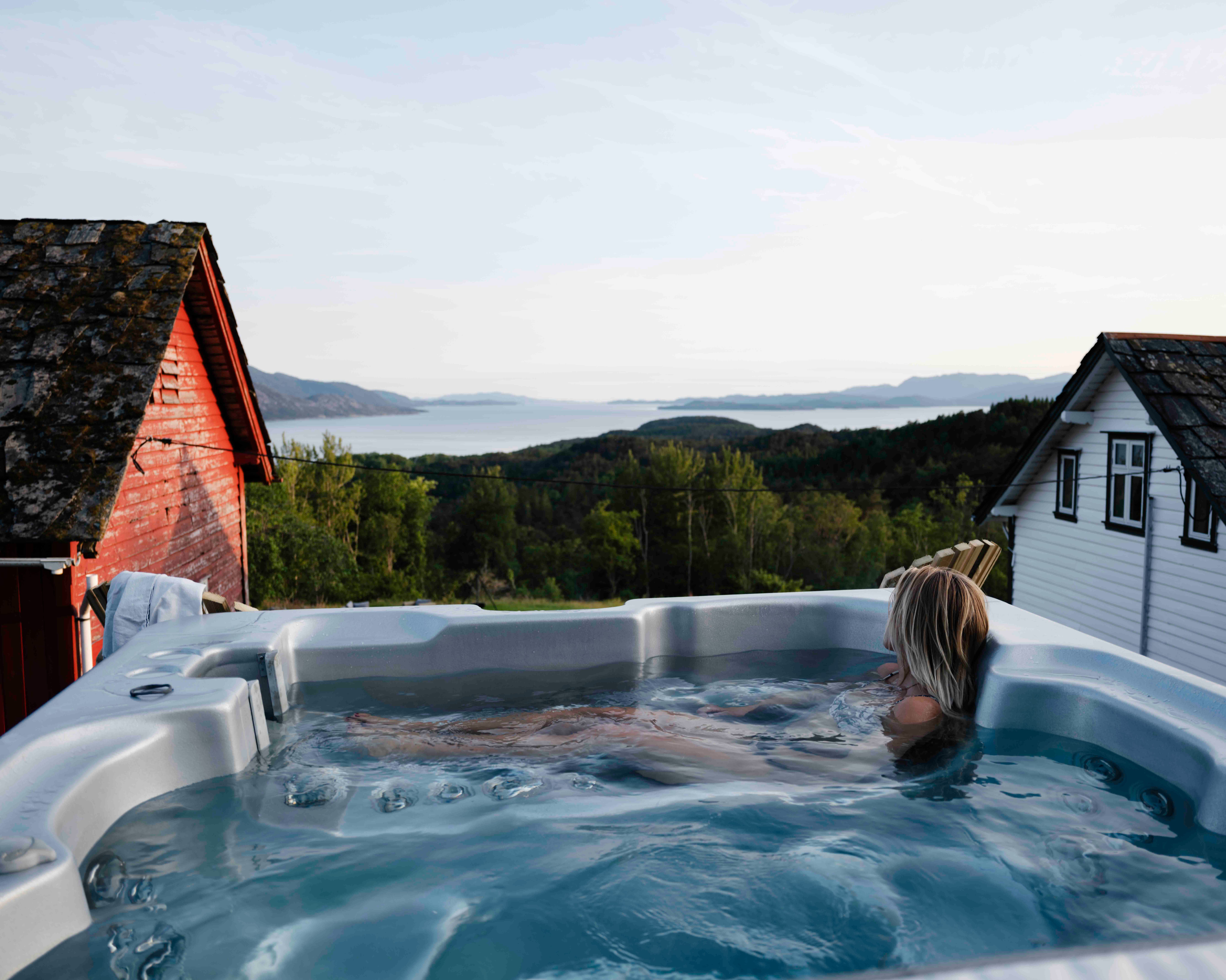 A woman in a hot tub outside of a fjord lodge, Hardangerfjord.
