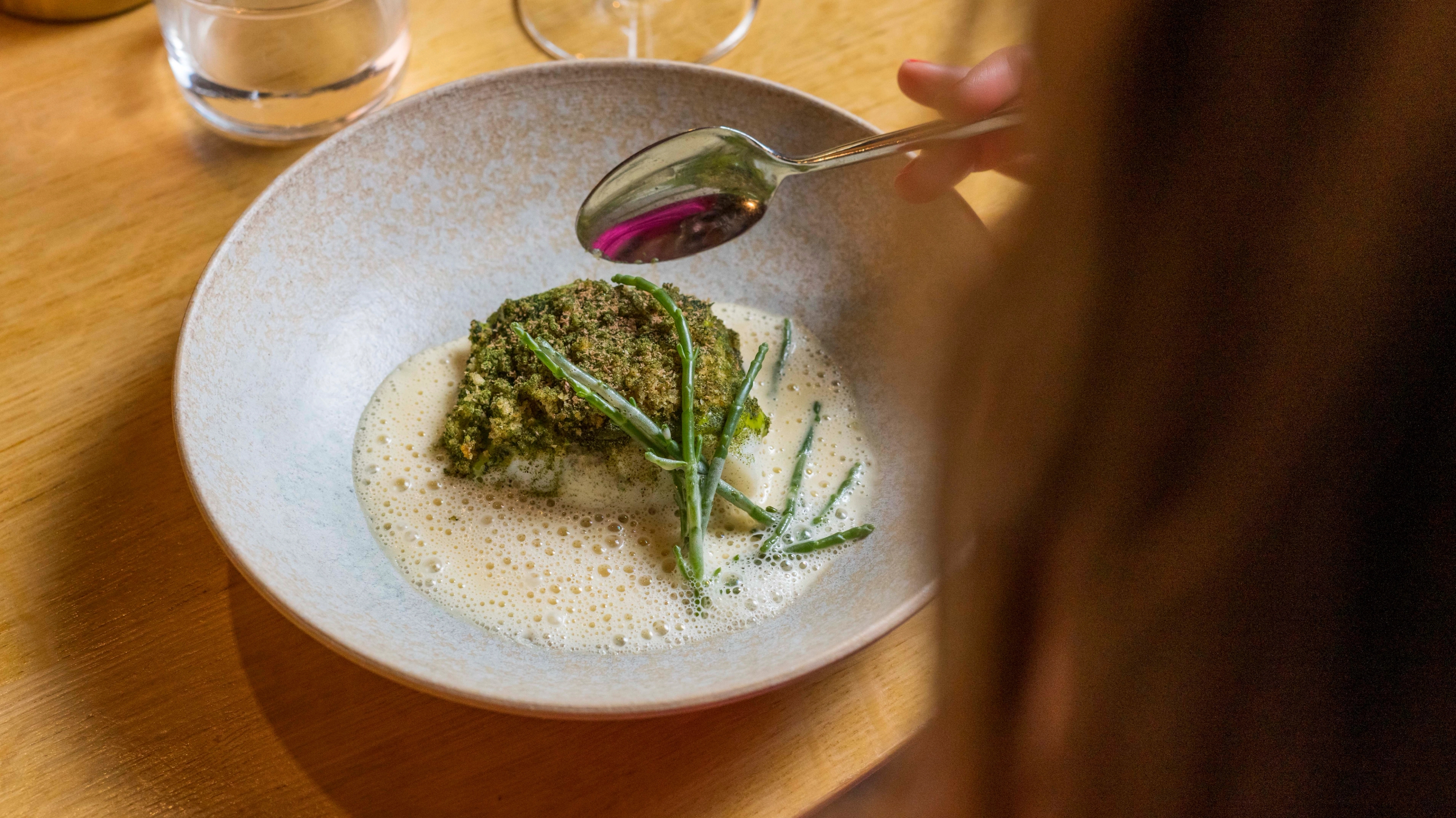 Woman with a plate of cod from Borgundfjord at Bro restaurant in Ålesund
