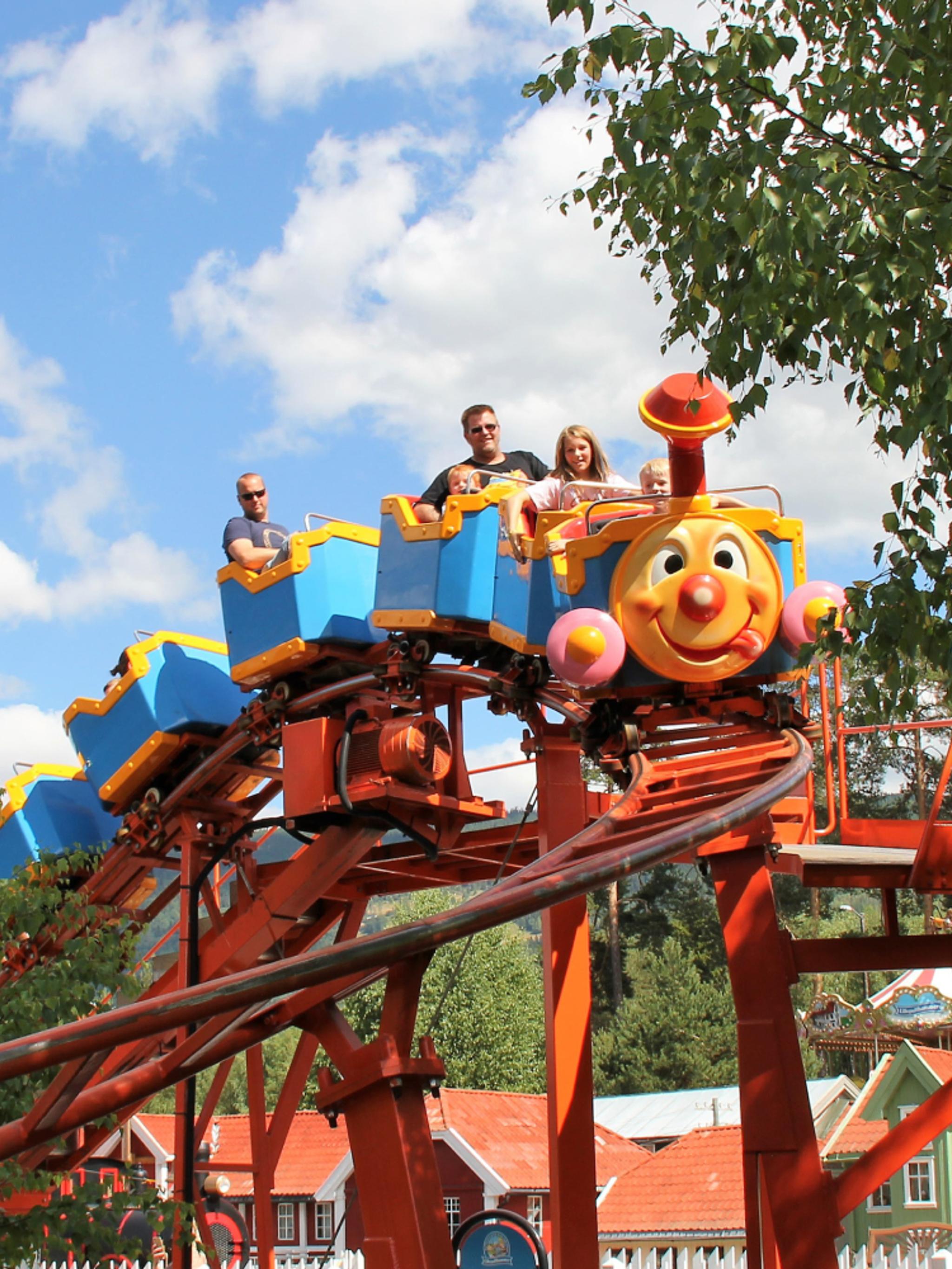 A family riding a carousel in Lilleputthammer amusement park, Norway