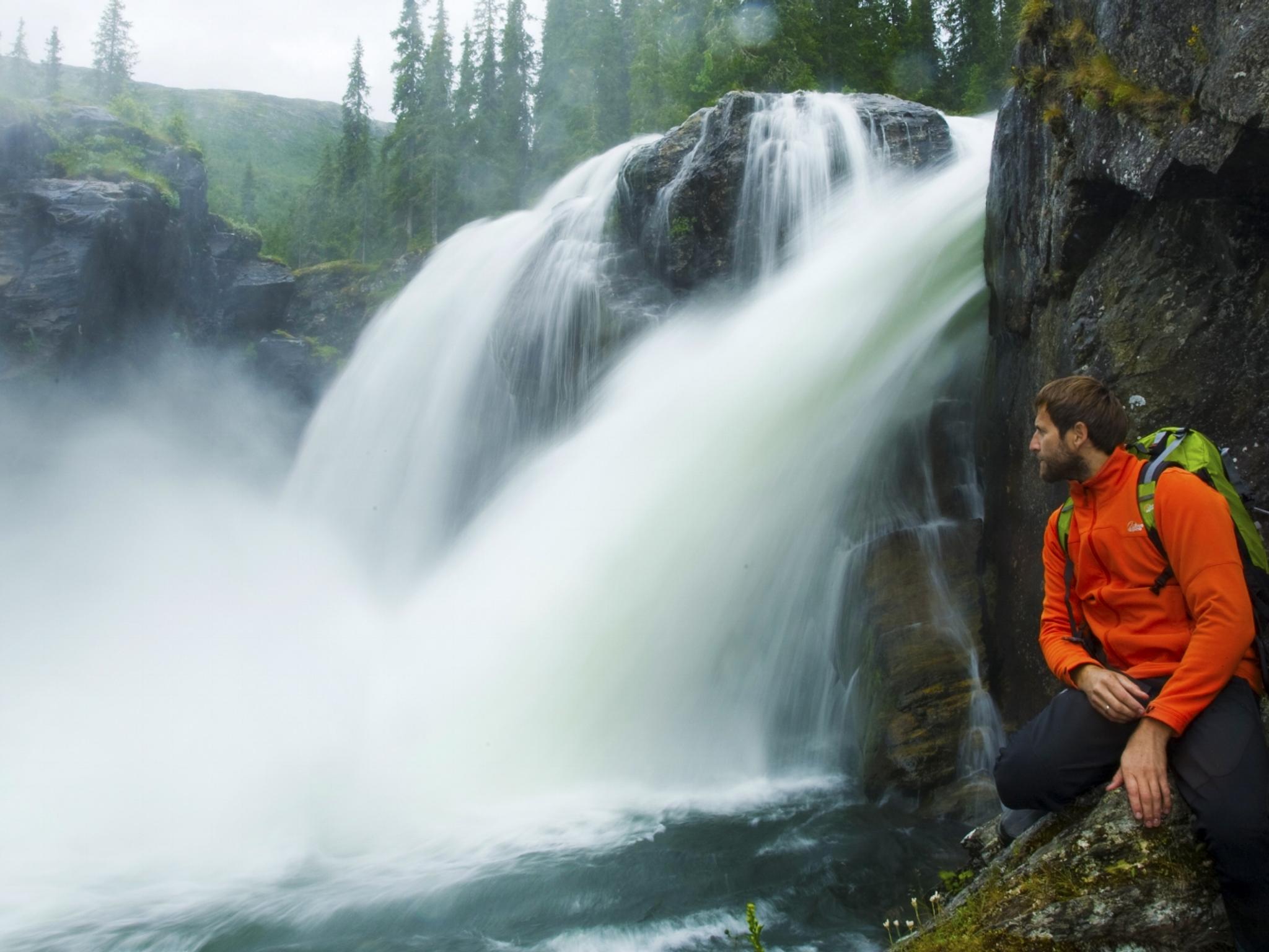 Ein Mann kniet neben dem Wasserfall Rjukandefossen in Hemsedal