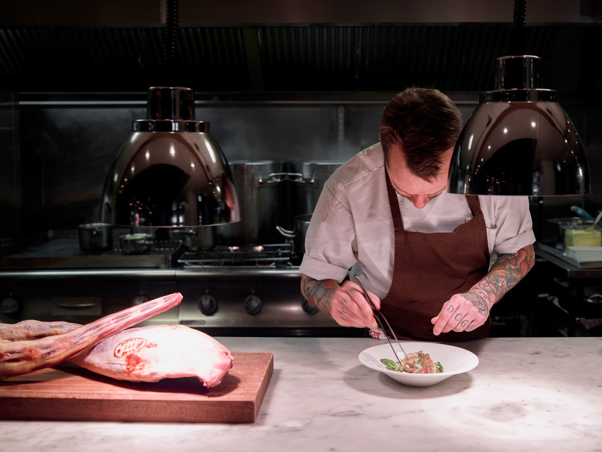 A chef preparing a dish in the kitchen at Bare Restaurant in Bergen, Fjord Norway