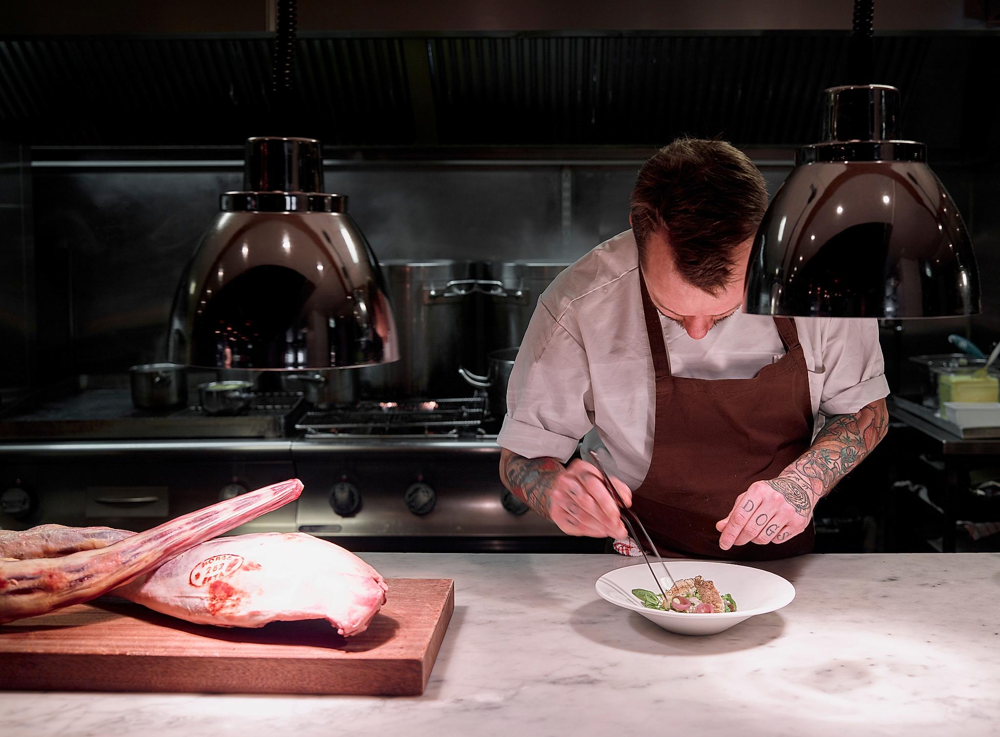A chef preparing a dish in the kitchen at Bare Restaurant in Bergen, Fjord Norway