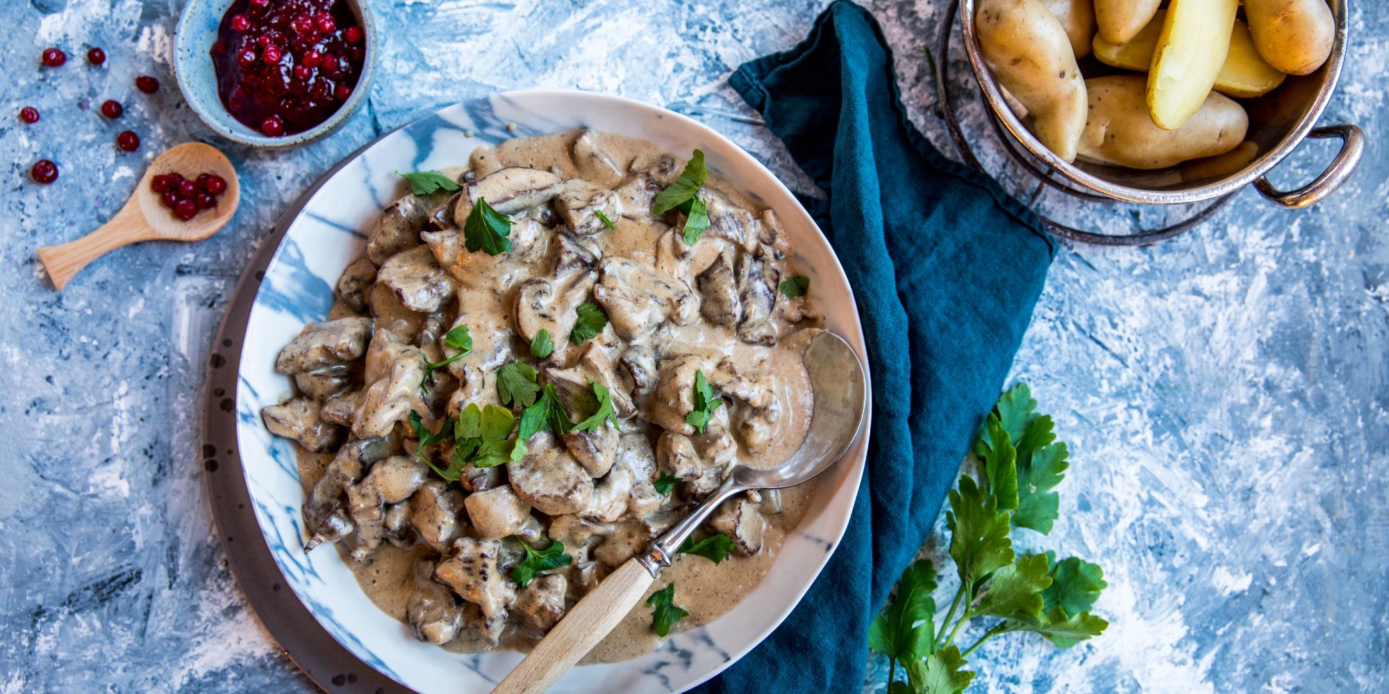 A plate of red deer stew served with potatoes and lingonberry