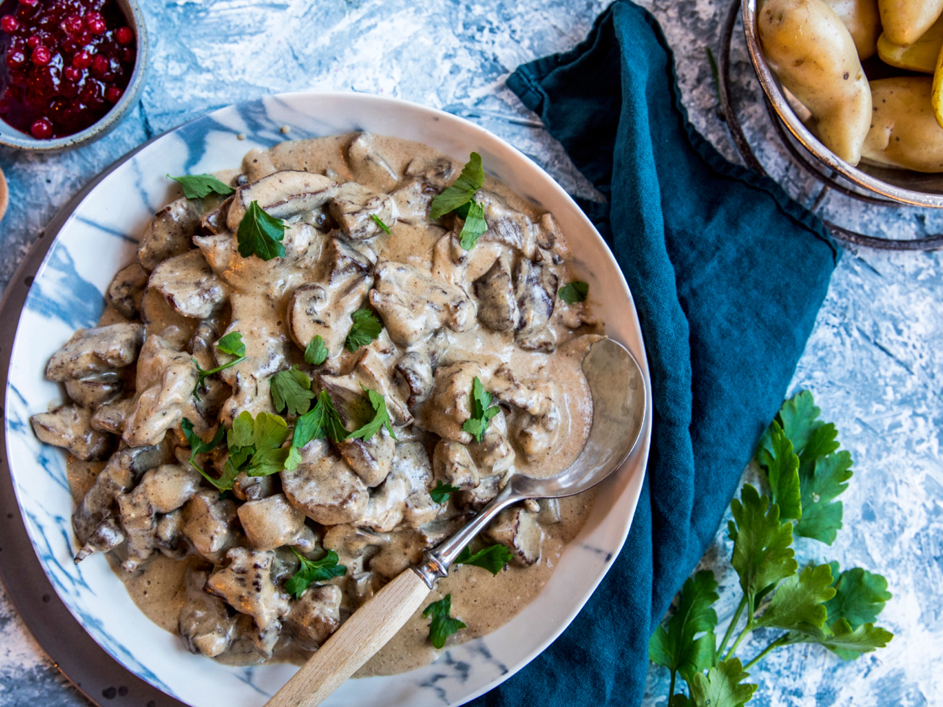A plate of red deer stew served with potatoes and lingonberry