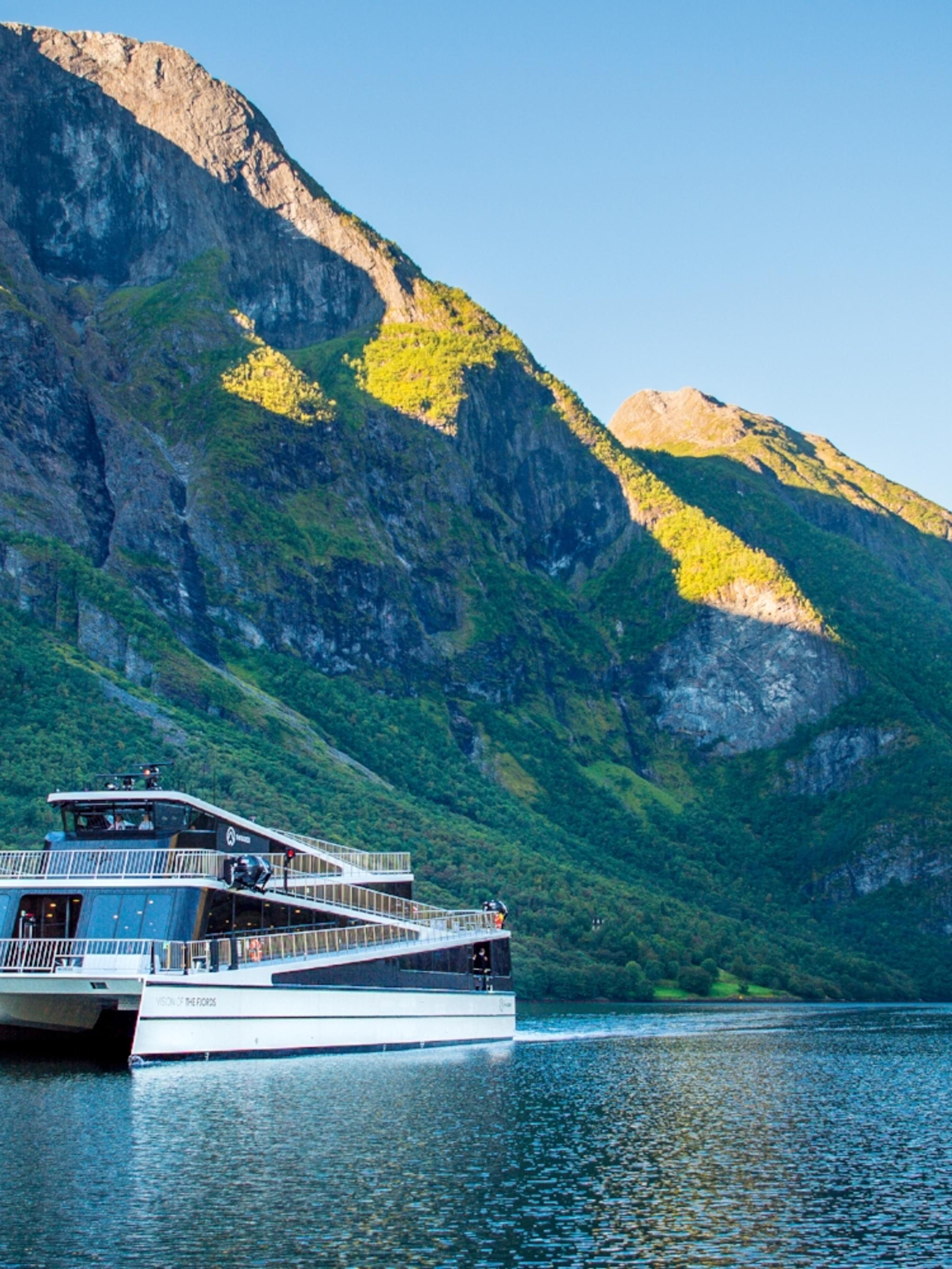 The hybrid electric vessel Vision of the Fjords cruising the Aurlandsfjorden fjord surrounded by mountains