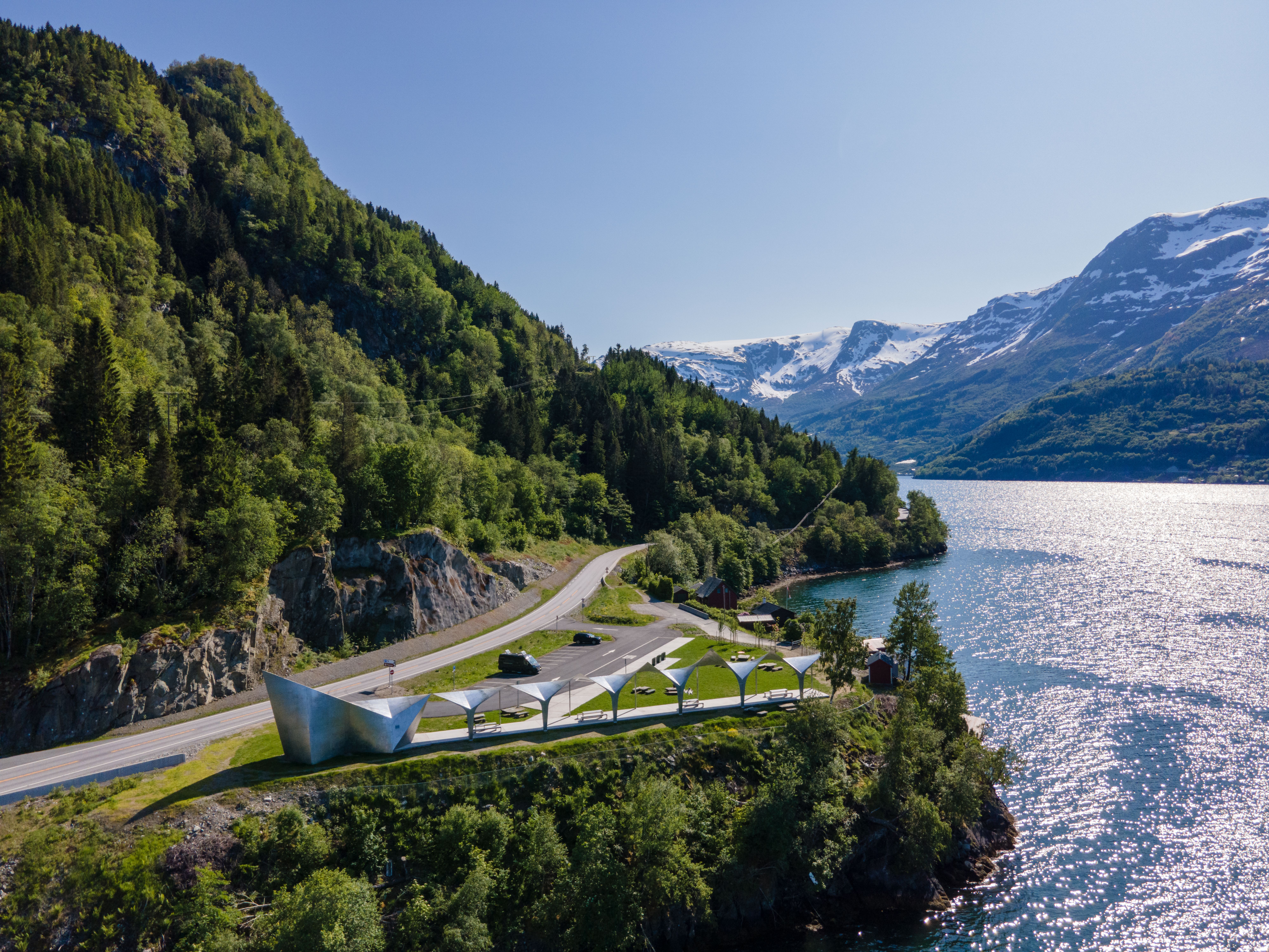 An overview of a silver geometric toilet building in nature.