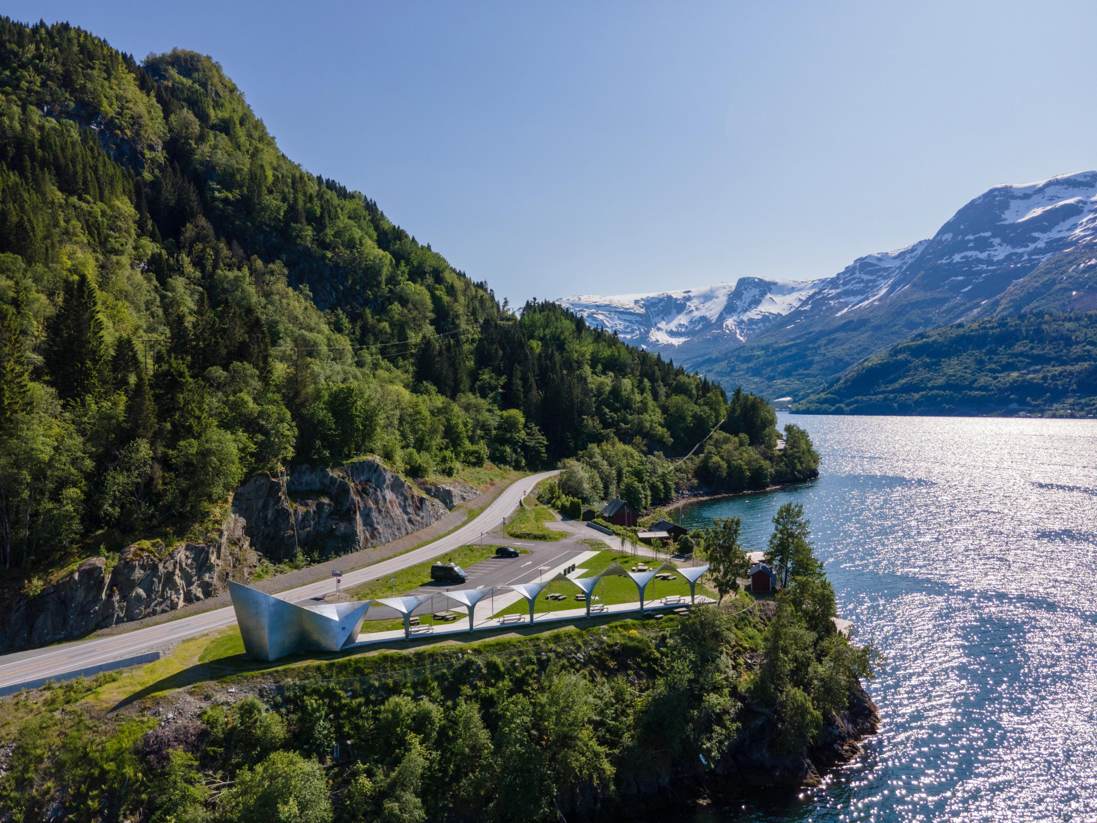 An overview of a silver geometric toilet building in nature.