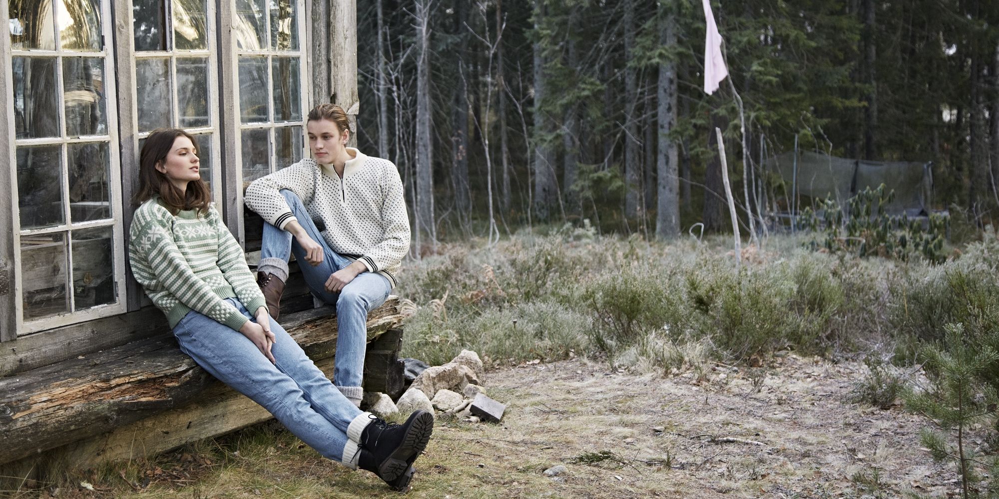 Two girls sitting on a bench outside, wearing woollen pullovers