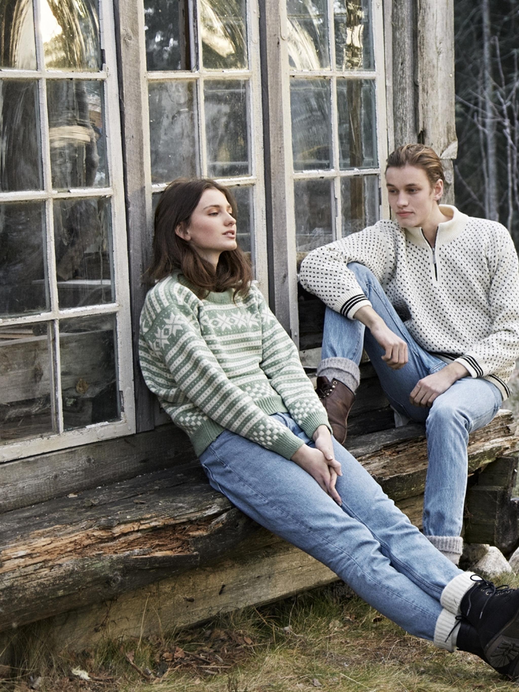 Two girls sitting on a bench outside, wearing woollen pullovers